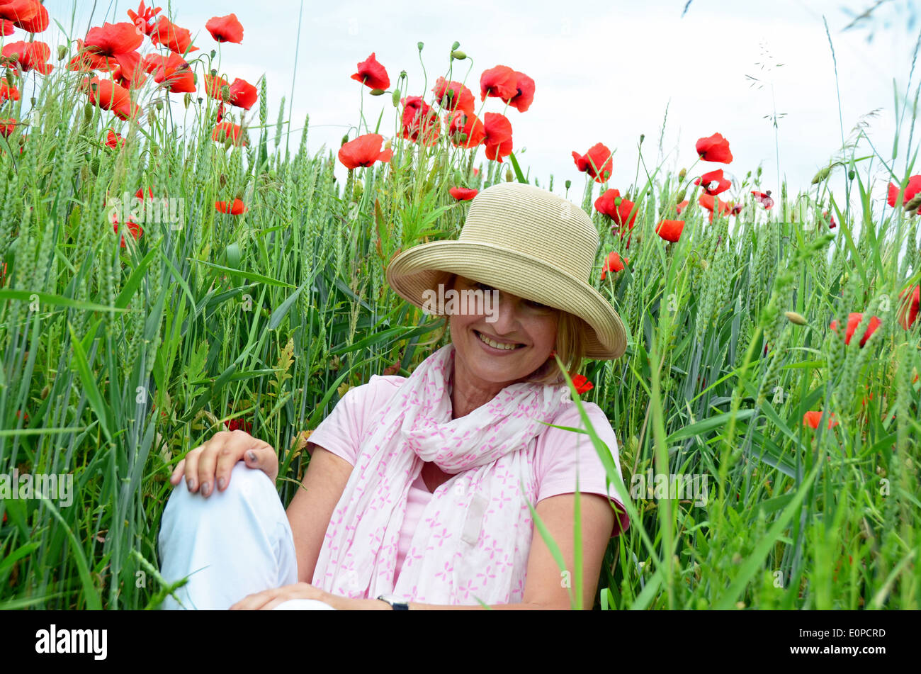 Frau mit Hut sitzt auf Wiese Stockfoto
