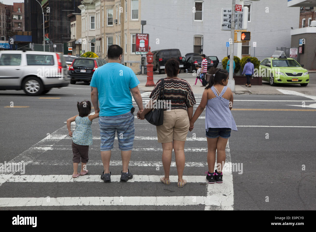FGamily Hand in Hand als sie überqueren eine belebte Kreuzung zusammen in Brooklyn, New York. Stockfoto