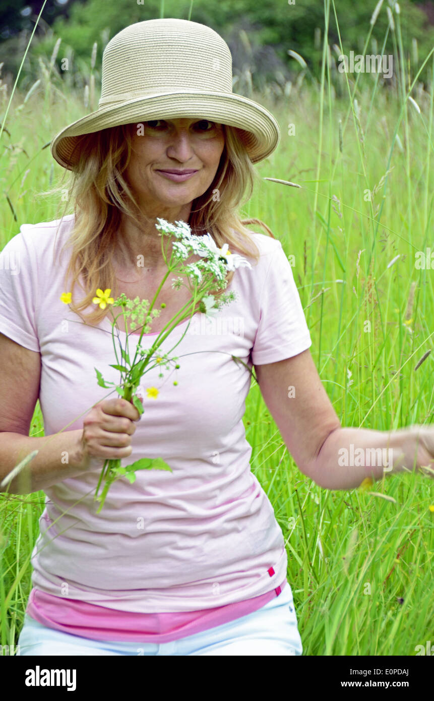 Frau mit Hut, die Blumen pflücken Stockfoto