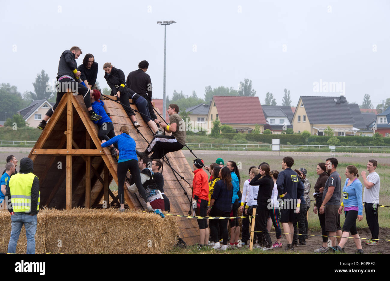 Berlin, Deutschland. 18. Mai 2014. Hobbyläufer steigen über ein Hindernis während der sogenannten Zombie-Run auf der Trabrennbahn Karlshorst in Berlin, Deutschland, 18. Mai 2014. Die Läufer tragen kleine Fahnen in den Gürtel, die sie haben, sicher über die Ziellinie zu gelangen, während die Zombies versuchen, sie zu stehlen. Das Sportereignis basiert auf der US-Fernsehserie "The Walking Dead". Foto: SOEREN STACHE/DPA/Alamy Live-Nachrichten Stockfoto