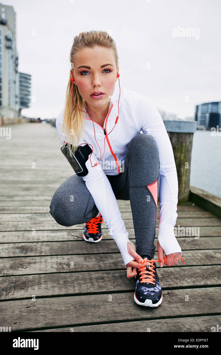 Hübsche junge Frau vor einem Lauf ihre Schnürsenkel zu binden. Passen Sie die junge weibliche Läufer Training im Freien. Stockfoto