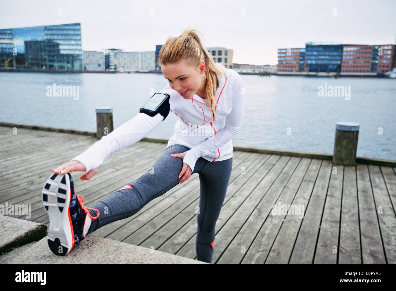 Passen Sie die junge Frau vor einem Lauf dehnen. Junge weibliche Läufer dehnen Sie ihre Muskeln vor einer Trainingseinheit Stockfoto