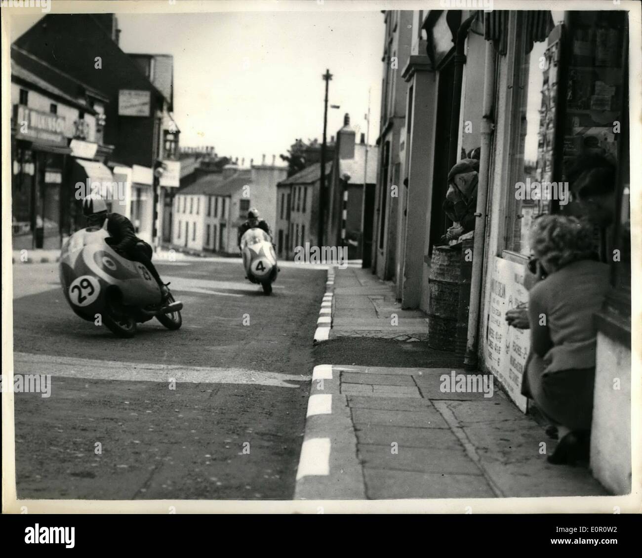 6. Juni 1957 - t.t. Rennen auf der Isle Of Man, Sanford gewinnt die 250 c.c.: C. Sanford Reiten eine Mondial, gestern gewann die 250 C.C International t.t. Rennen auf der Isle of man. Photo zeigt C. Sanford (29) und Sammy Miller (Nr. 4) erste und fünfte bzw. Geschwindigkeit während des Rennens gesehen, als Zuschauer von Shop Türen zu suchen. Stockfoto