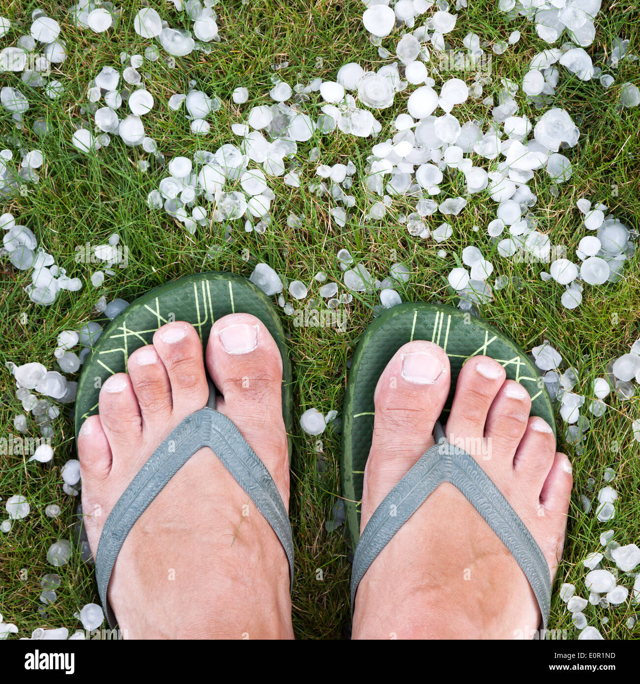 Mann mit Flip Flops stehen auf dem Rasen mit Hagel nach Hagelschlag Stockfoto