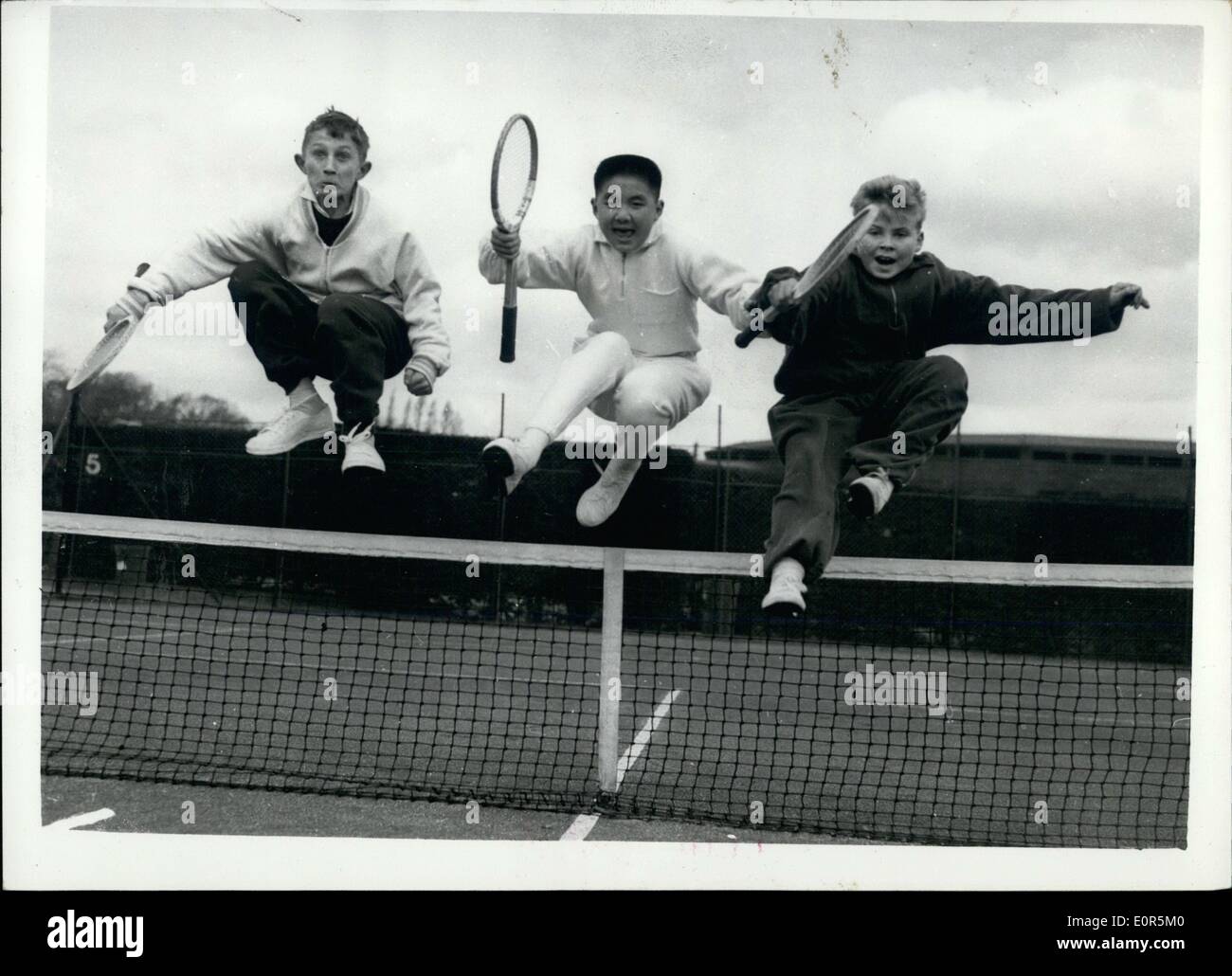 4. April 1958 - Tennisunterricht für Kinder und Jugendliche durch einen Sprung im Netz warm zu halten: Tennis-Stars der Zukunft beteiligen sich an der Lawn Tennis Association Ostern Ausbildungsstätte in Wimbledon. Das Foto zeigt drei der Jugendlichen sprang über die Net - warm - in Wimbledon Vormittag zu halten. Sie sind L-r: Clive Jarrett(13) Derby; Jerry (12) gesungen von Kew und Ian Stevens (12) von Esher. Stockfoto