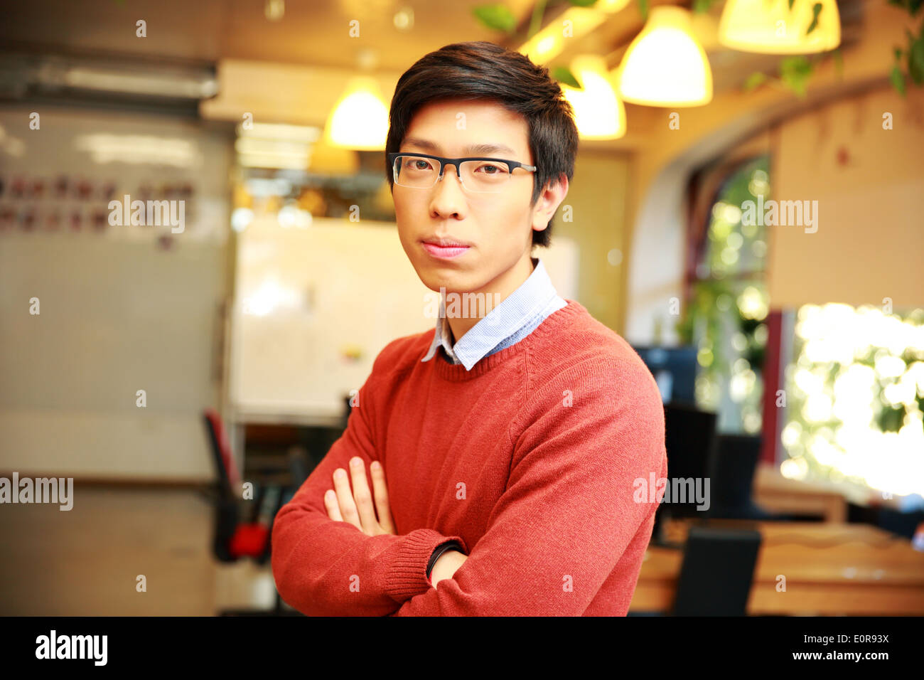 Nachdenklich asiatischen männlichen Schüler Arme gefaltet steht im Klassenzimmer Stockfoto