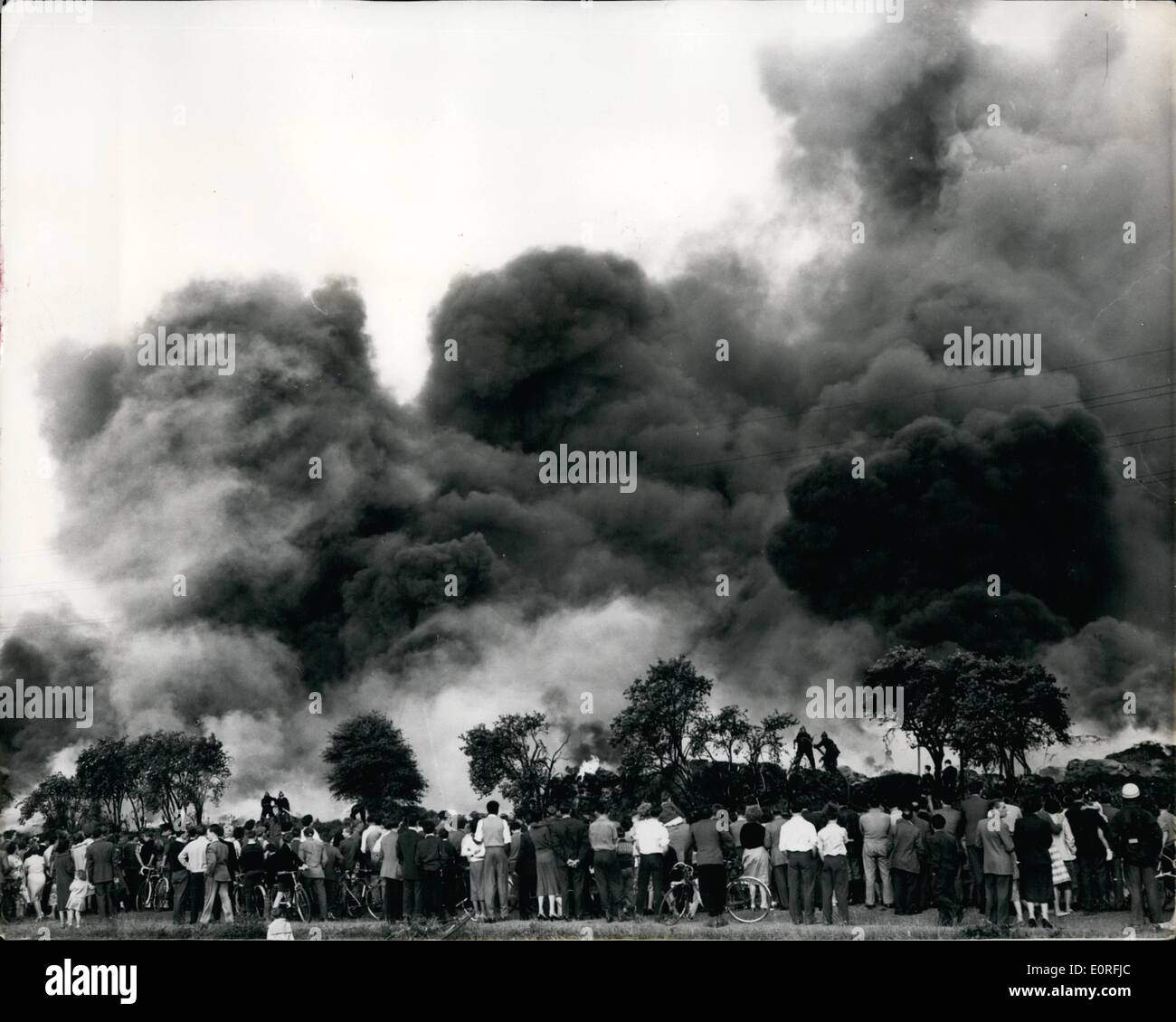 6. Juni 1959 - Tausende entpuppen sich Feuer in North London Rubber Dump. beobachten: Tausende erwies sich als um weiße Feuerwehrleute kämpften die riesige Feuersbrunst ausgebrochenen an einen Schrott-Kautschuk-Dump in North London gestern zu sehen. Der Rauch war gesehen acht Meilen entfernt. So viele Autos kamen an Ort und Stelle, dass sie die Straßen blockiert und die Feuerwehrfahrzeuge behindert. Tausende von Tonnen Gummi war ruiniert, bevor Feuerwehrleute den Brand unter Kontrolle bekam. Das Foto zeigt Massen Uhr Feuerwehrleute Brandbekämpfung am Hale Wharf, Tottenham, gestern. Stockfoto