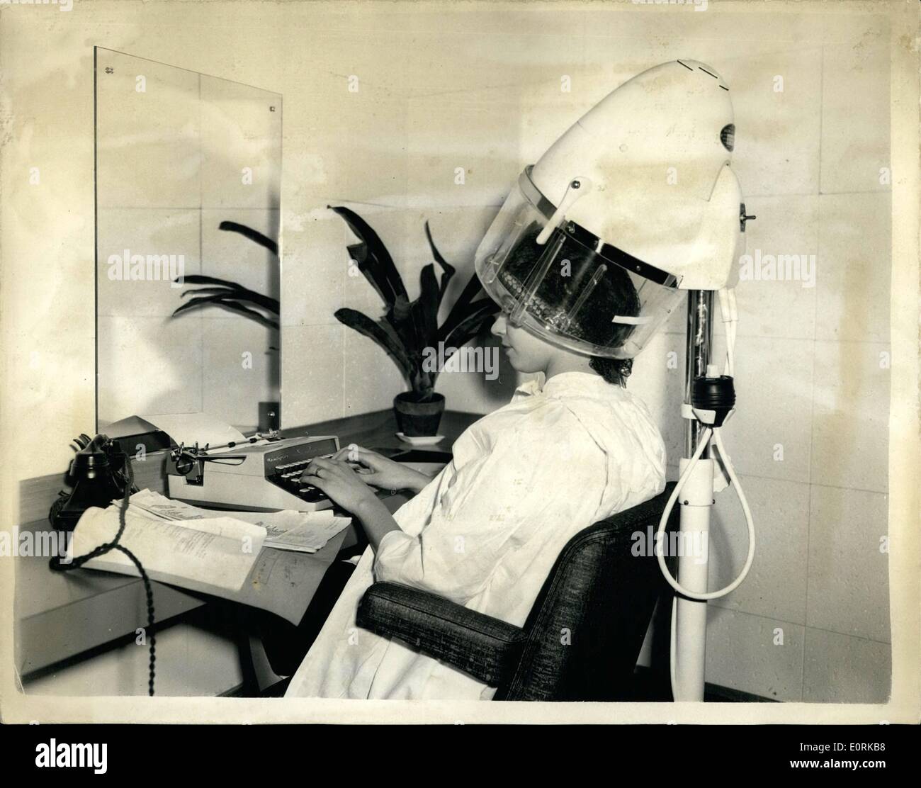 12. Dezember 1959 - eine '' Haare tun '' -, während Sie Art. Neuer Salon in Holborn Shop: Ein neue Stil-Coiffeur-Salon geöffnet wurde im Gamages Holborn Store - in dem der Kunde-in der Regel Schreibkräfte - Sekretärinnen und andere Büro-Arbeiter-kann ihre Eingabe fort, während ihr Haar, besucht wird. Telefone wurden in den Kabinen - wobei der '' Chef '' kann wenden Sie sich an seine Sekretärin und ihr Anweisungen - unter den Fön usw. installiert. Foto zeigt Miss Jean Walter von Forest Gate unter dem Haar Trockner - während Sie mit der Schreibmaschine - auf dem Gamages Salon heute Morgen. Sie hat das Telefon neben Stockfoto