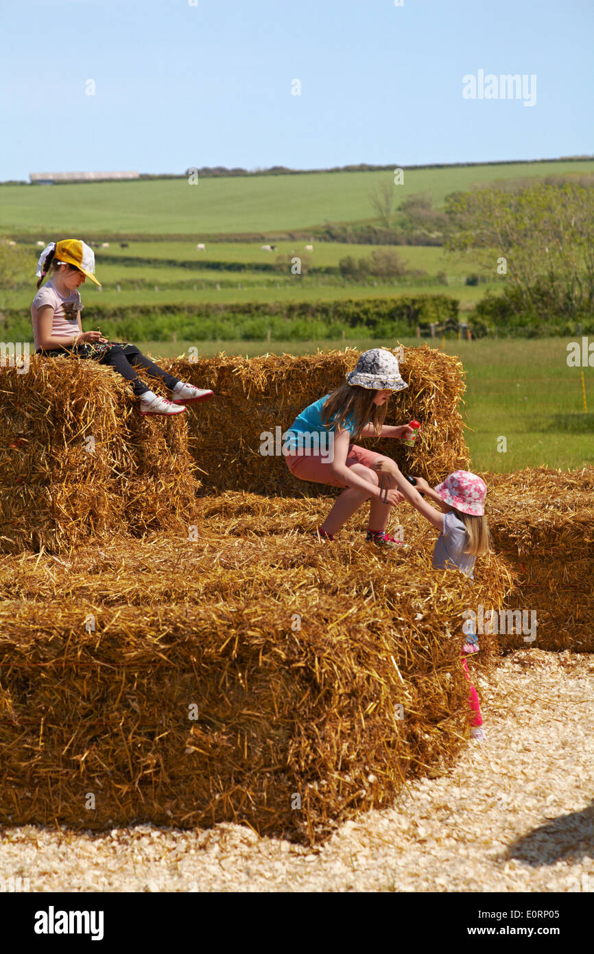 Drei junge Mädchen spielen im Stroh Heu Ballen bei Abbotsbury, Dorset UK an einem heißen sonnigen Tag im Mai Stockfoto