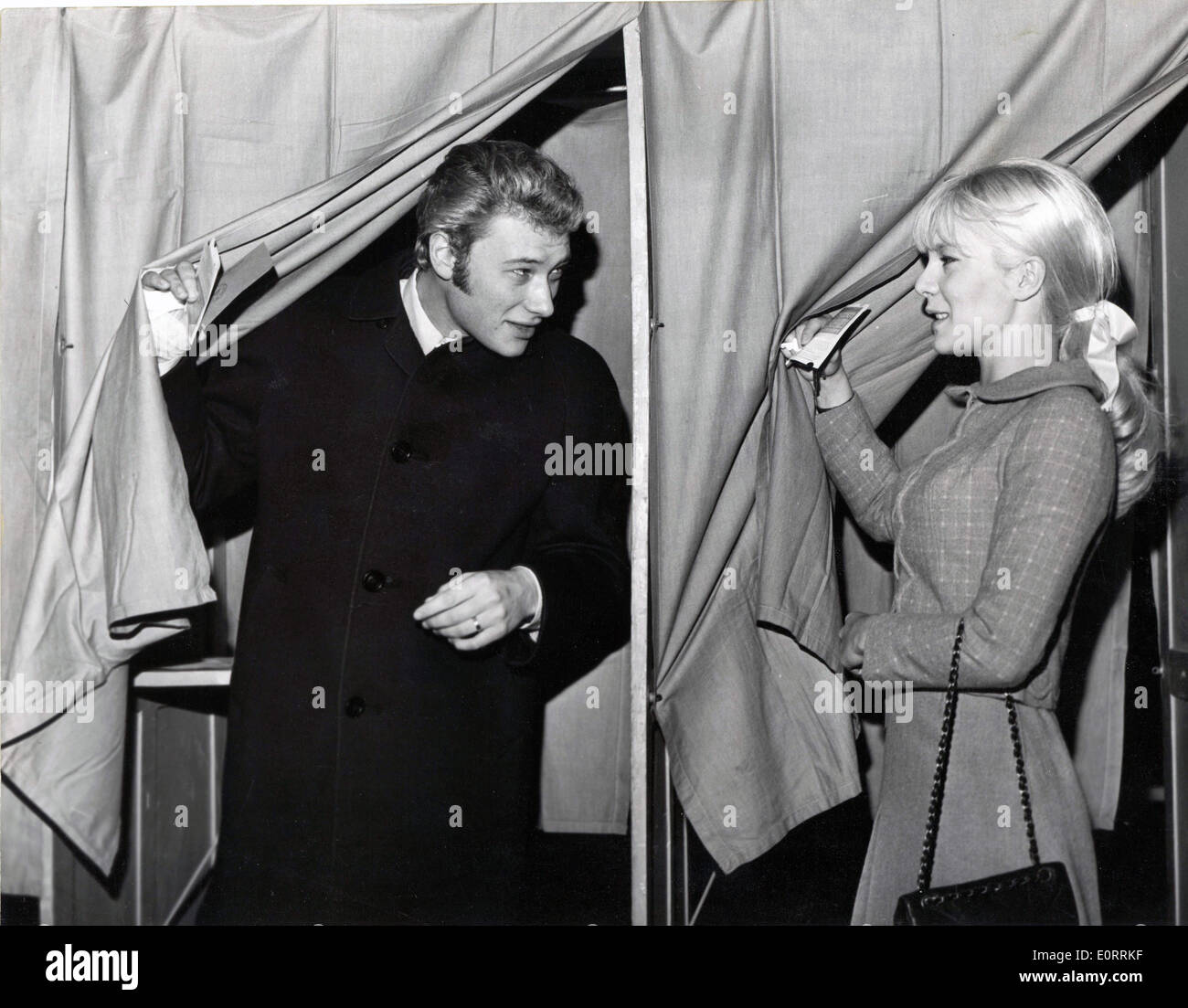 6. Mai 1960 - Paris, Frankreich - JOHNNY HALLYDAY herauskommt eine Wahlkabine, während seine Frau SYLVIE VARTAN geht, um sowie zu stimmen. Genaues Datum unbekannt. Stockfoto