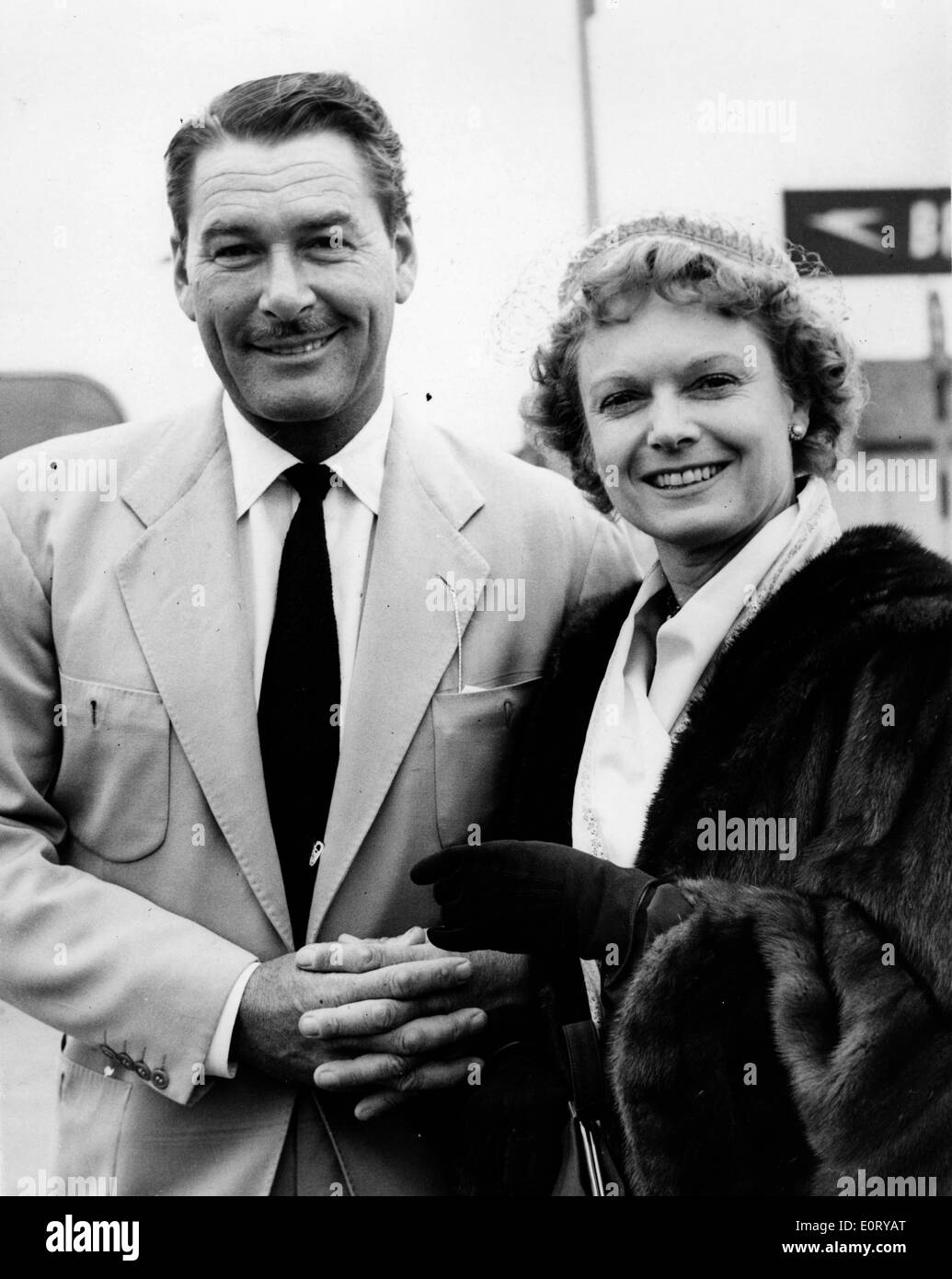 Schauspieler Errol Flynn am Flughafen mit einer Frau Stockfoto