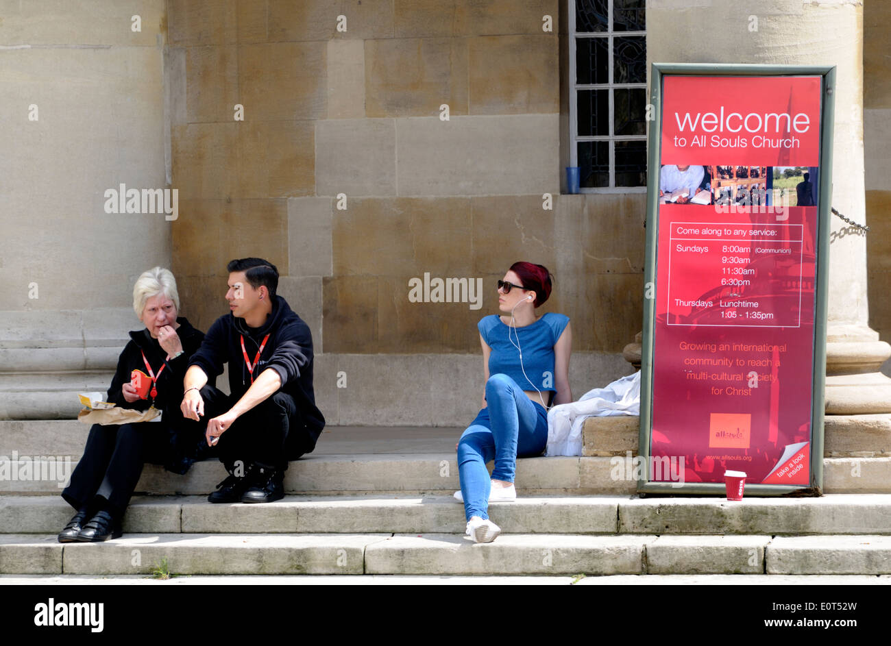 London, England, Vereinigtes Königreich. Leute sitzen auf den Stufen des All Souls Church, Langham Place, Regent Street Stockfoto