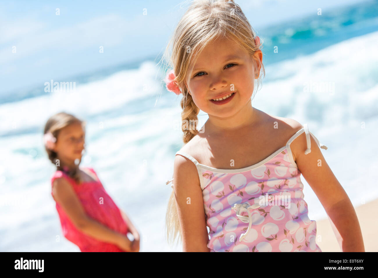 Porträt von niedlichen Mädchen am Strand mit Freund im Hintergrund hautnah. Stockfoto