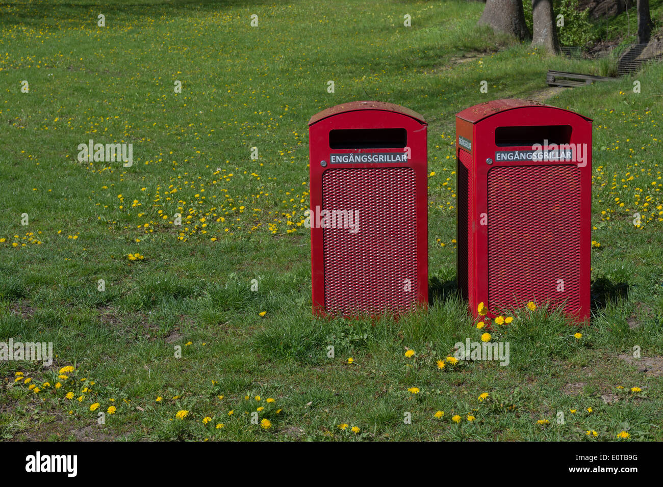 Zwei rote Mülltonnen mit Text "Engangsgrillar" für Einweg-Grill trash Elemente in einem Park, Stockholm, Schweden im Mai. Stockfoto