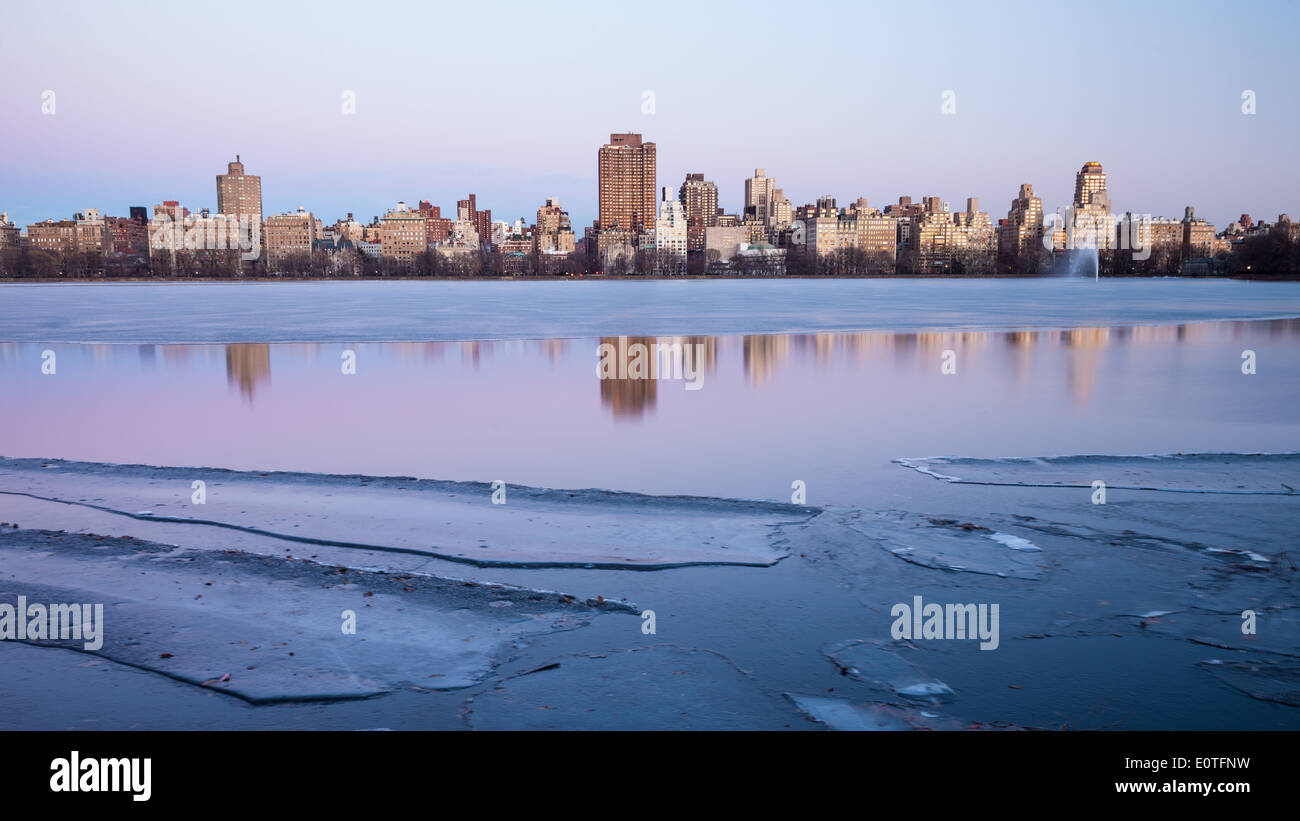 Gebäude reflektieren im Central Park Jacqueline Kennedy Onassis zugefrorenen See im Winter Sonnenuntergang. New York Stockfoto