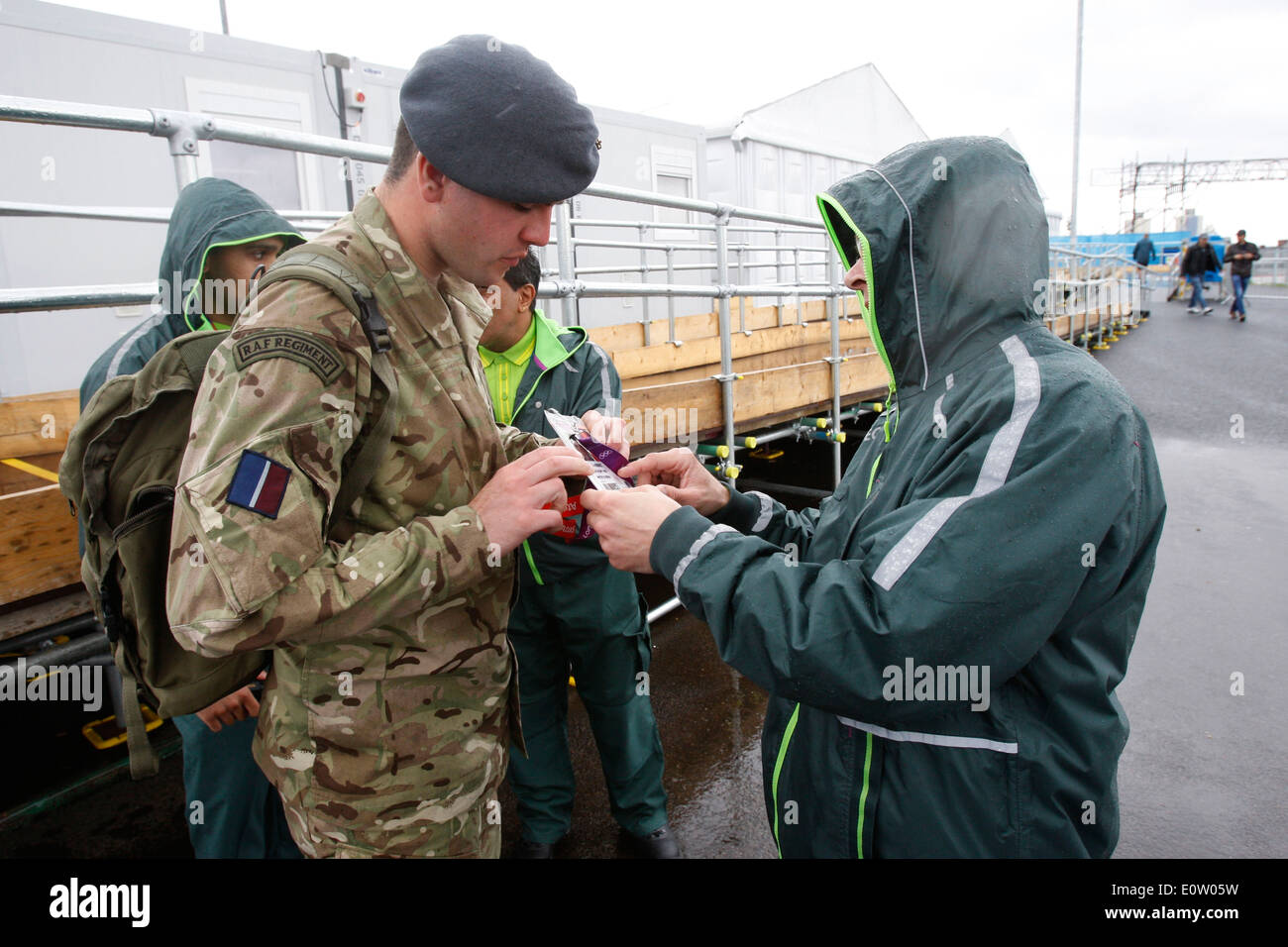 Die G4S Security Personal prüft den Pass eines britischen Soldaten im Olympia-Park in Stratford in London, Großbritannien, 16. Juli 2012. London ist Gastgeber für die Olympischen Spiele 2012, die vom 27. Juli bis 12. August 2012 stattfinden wird und die Paralympischen Spiele vom 29 August bis 9. September 2012. Stockfoto