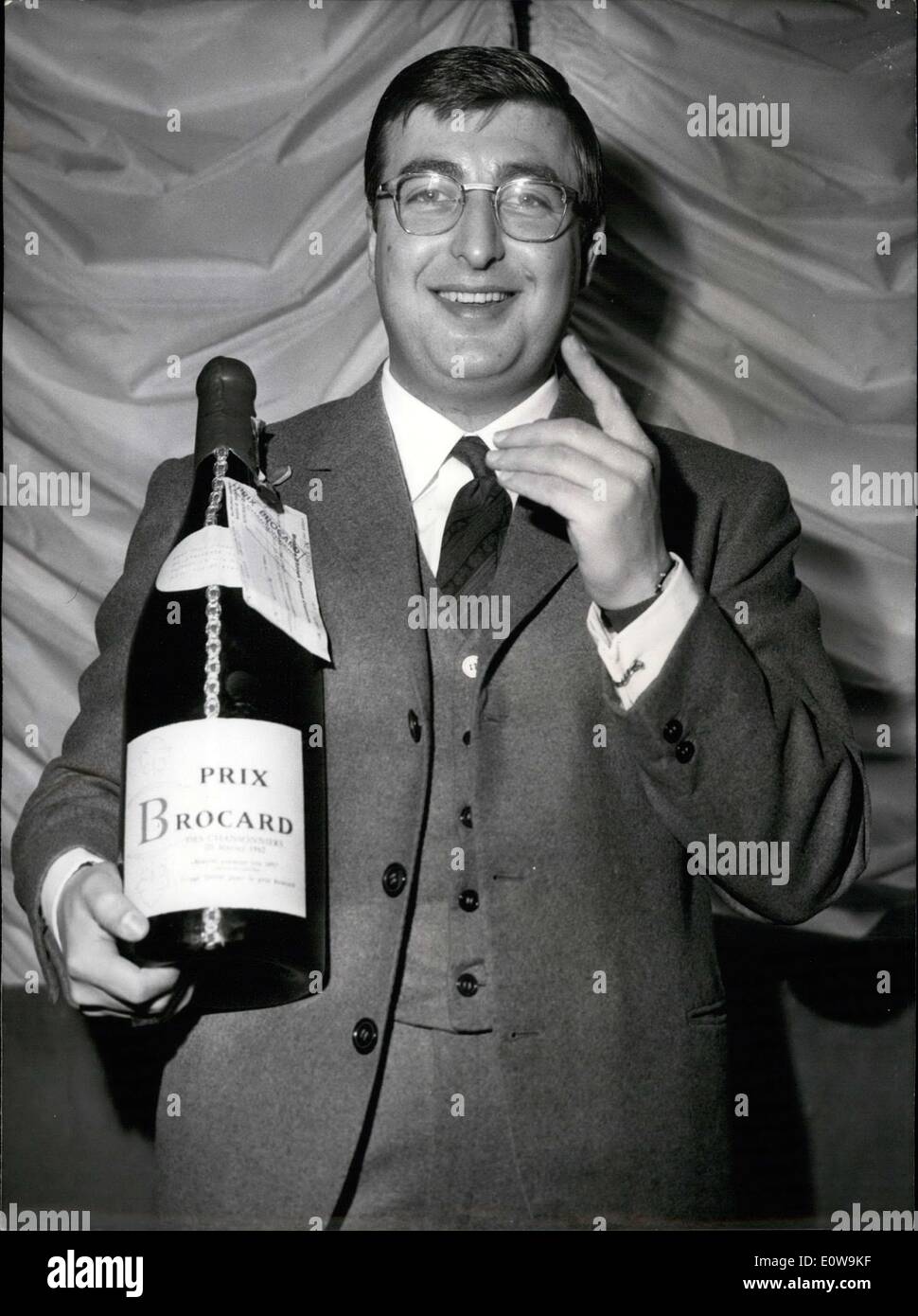 20. Februar 1962 - Henry Tisot gewinnt den Prix Brocard 1962. Henry Tisot hält eine Magnum Flasche Beaujolais mit einem Scheck für eine große Summe Geld, die zu ihm angebracht. Er hebt seine Hand als wäre er ein paar Worte sagen. Stockfoto