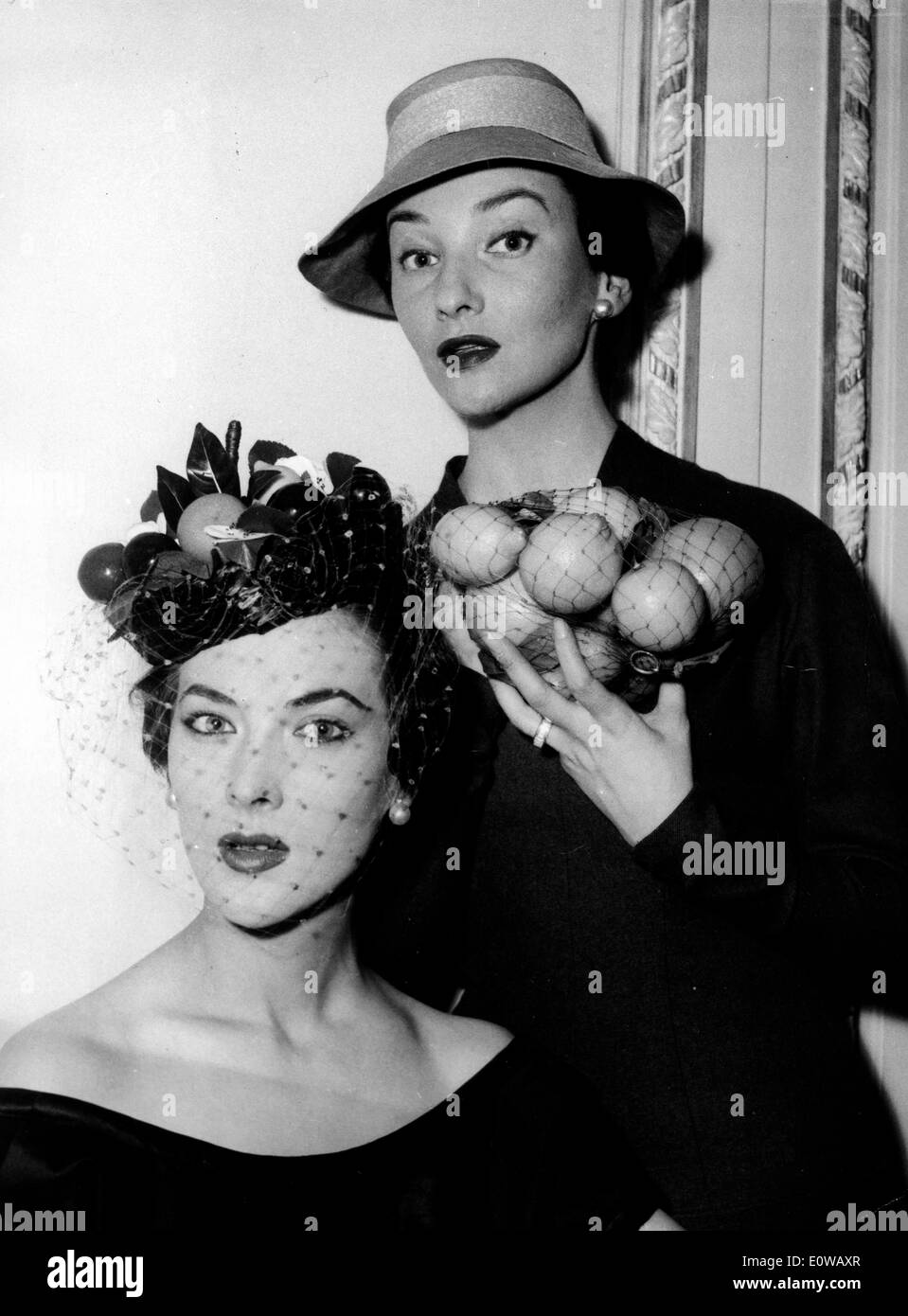 Zwei Modelle mit Hüten bedeckt eine Frucht Stockfoto