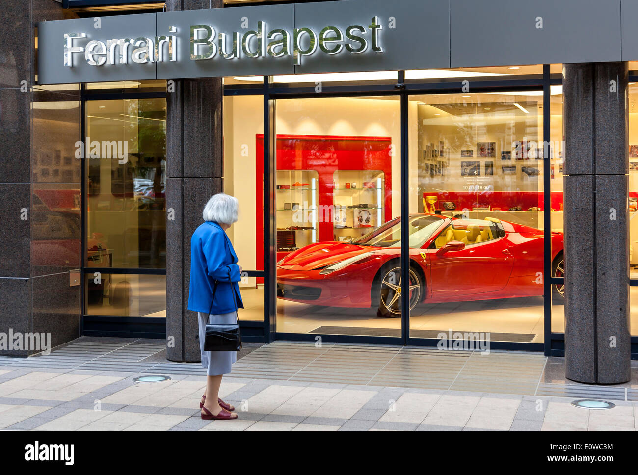 Ältere Frau stand vor dem Schaufenster von einem Ferrari-Vertragshändler, Budapest, Ungarn Stockfoto
