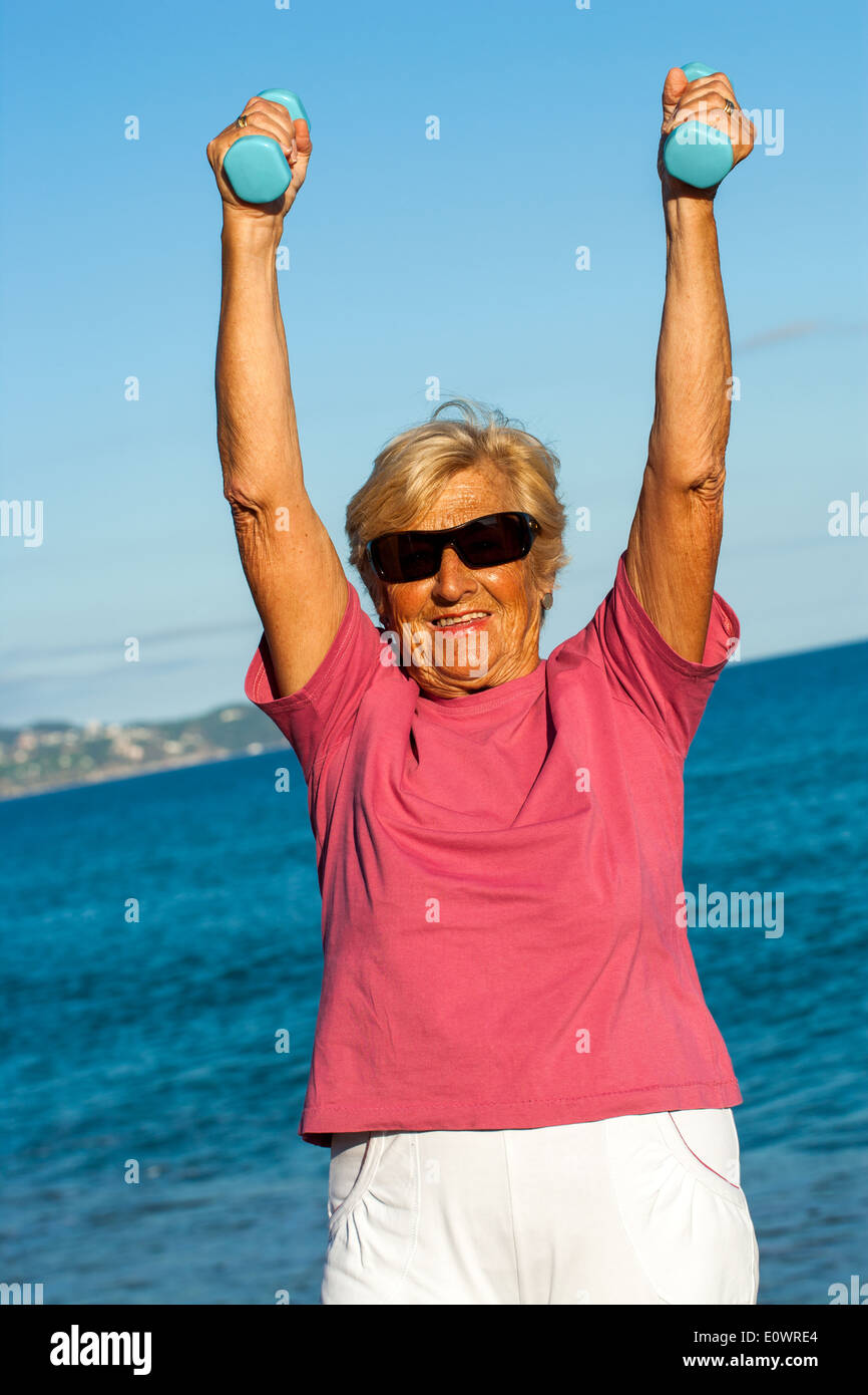 Ältere Frau Muskel Übung am Strand. Stockfoto