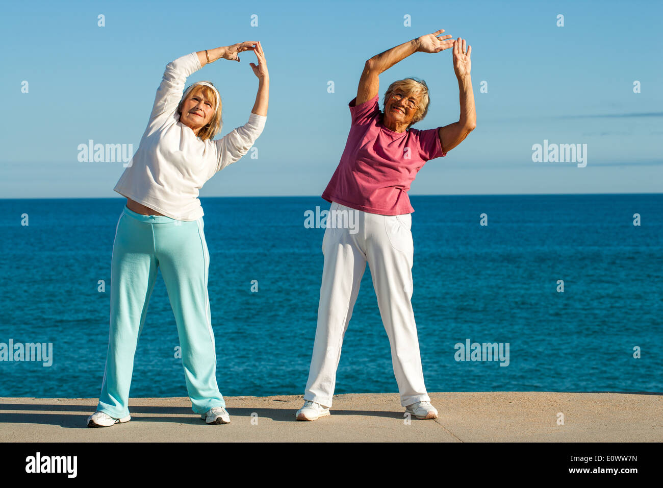 Porträt von Seniorenfitness Damen Strecken Arme zusammen am Meer. Stockfoto