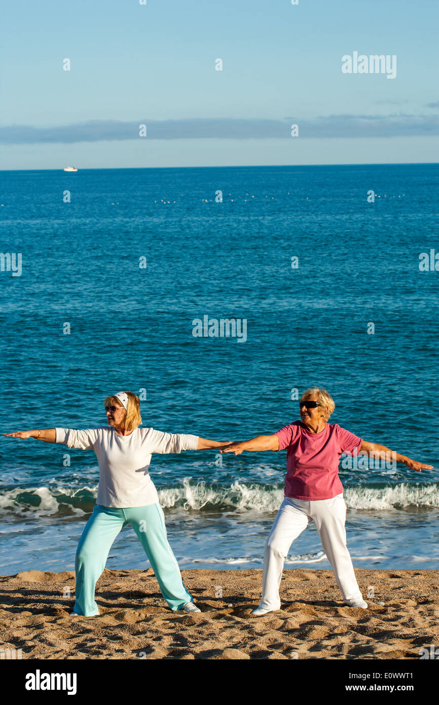 Zwei ältere Damen Yoga-Übungen am Strand. Stockfoto