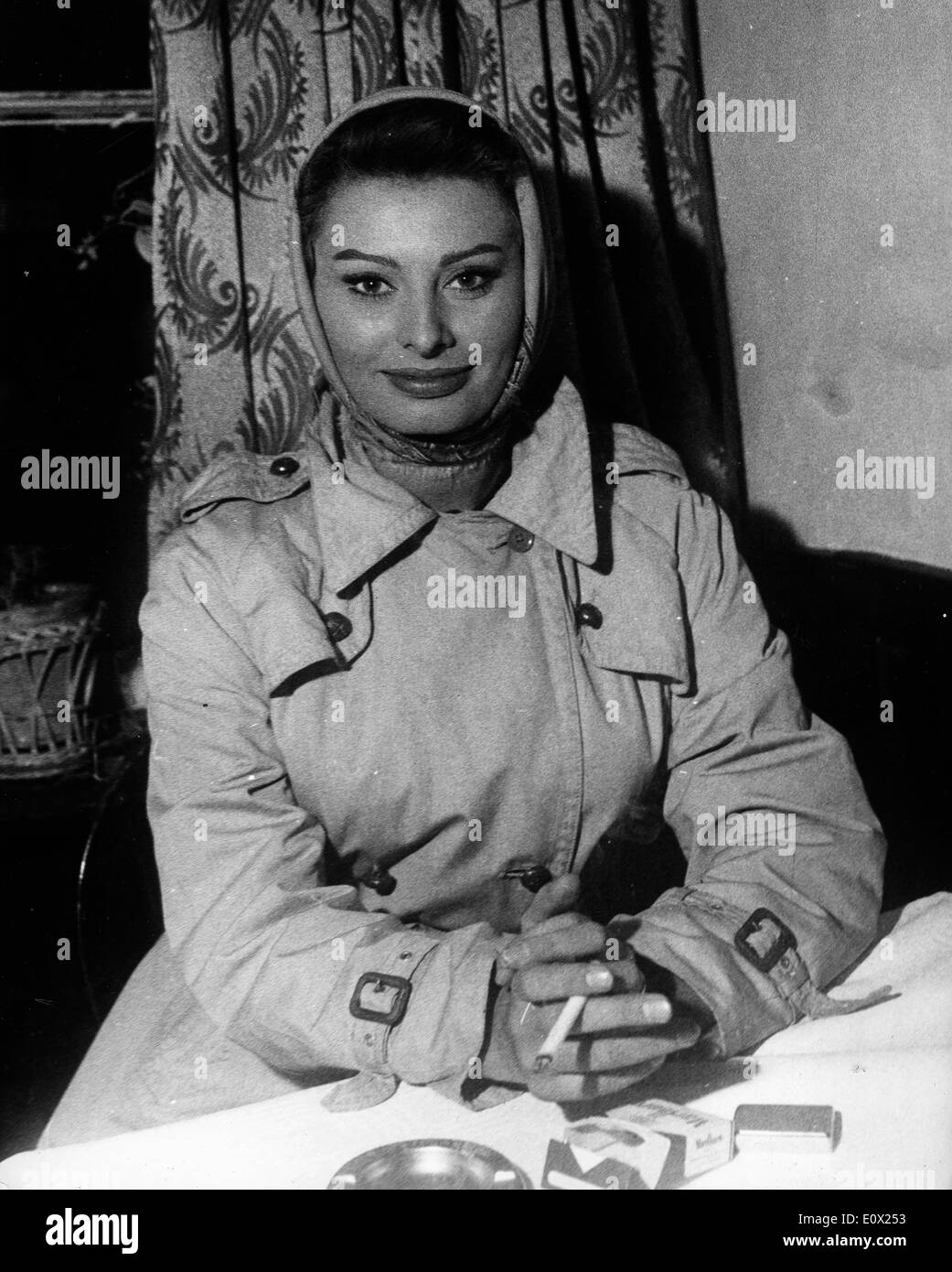 Schauspielerin Sophia Loren in ein Trenchcoat, eine Zigarette rauchend Stockfoto