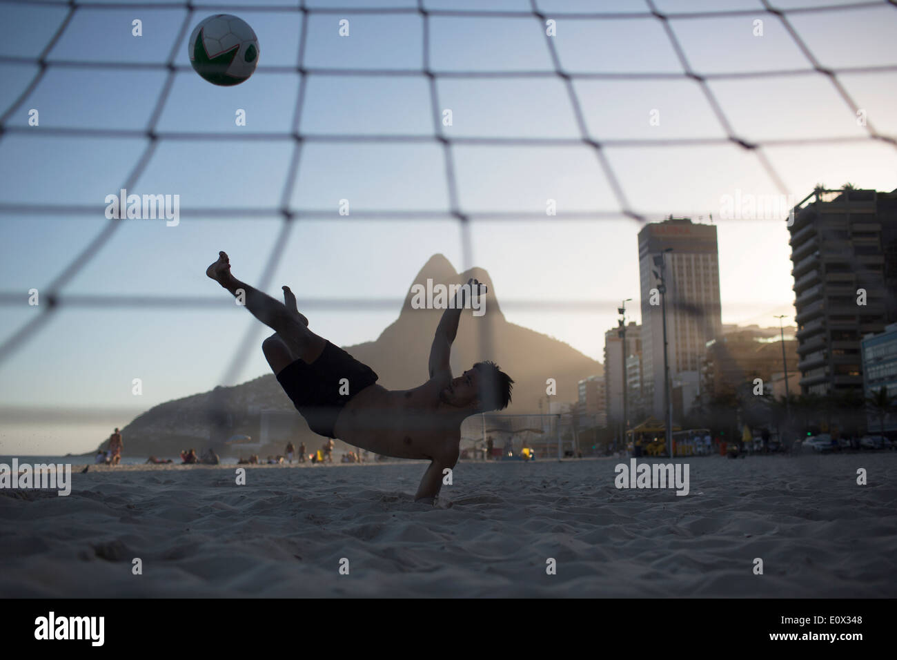 Ein Fußballer erzielt akrobatisch ein Tor aus einem Bicyclette Overhead Fußball Kick am Strand von Ipanema in Rio De Janeiro, Brasilien Stockfoto