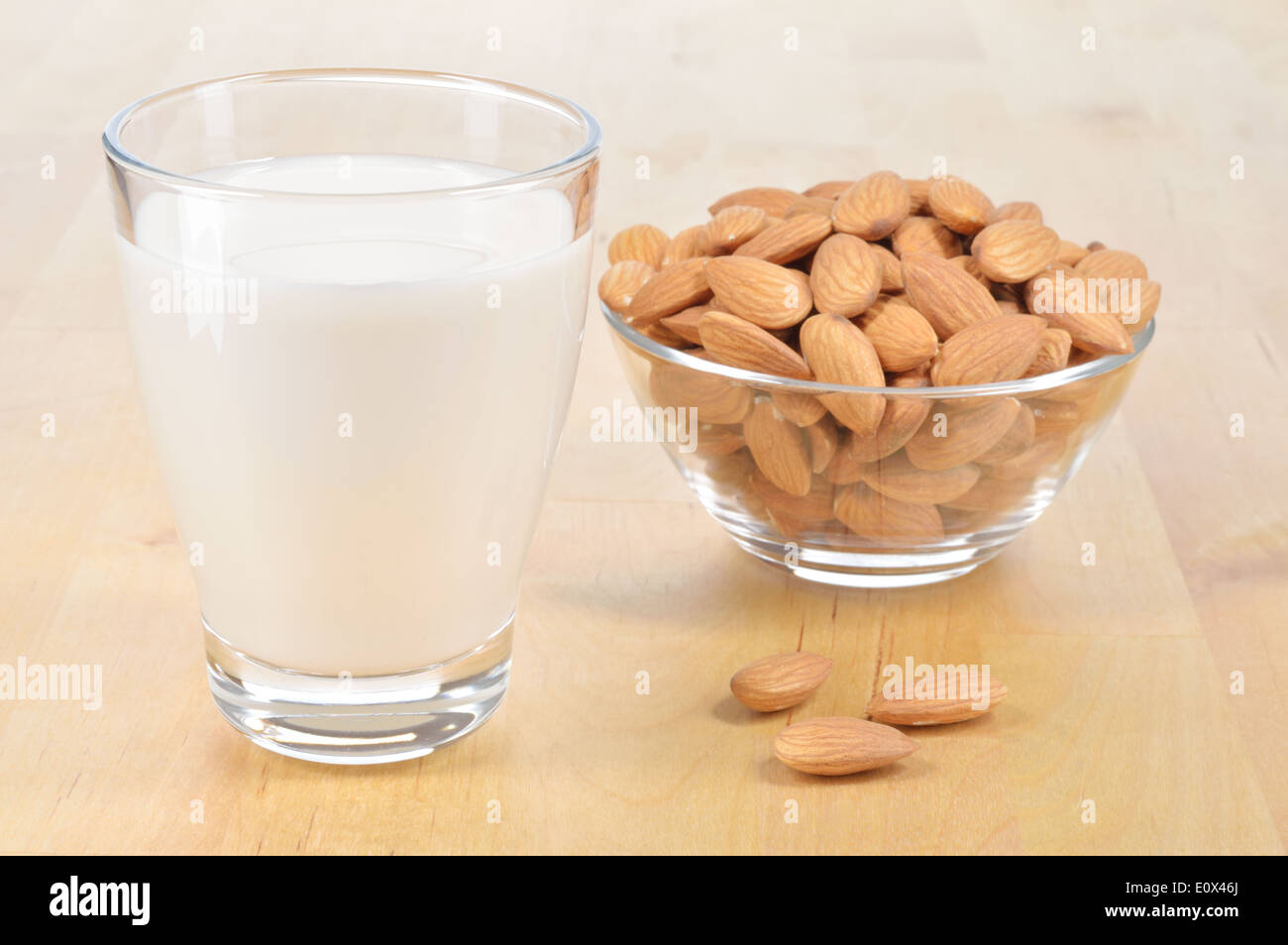 Mandel-Milch als Ersatz für Kuhmilch. Glas Mandelmilch und Schüssel mit Mandeln auf einem Holztisch. Stockfoto