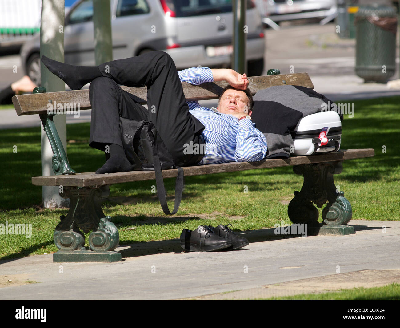 Geschäftsreisende, die zum Entspannen in der Sonne auf einer Bank im Park in Brüssel, Belgien Stockfoto