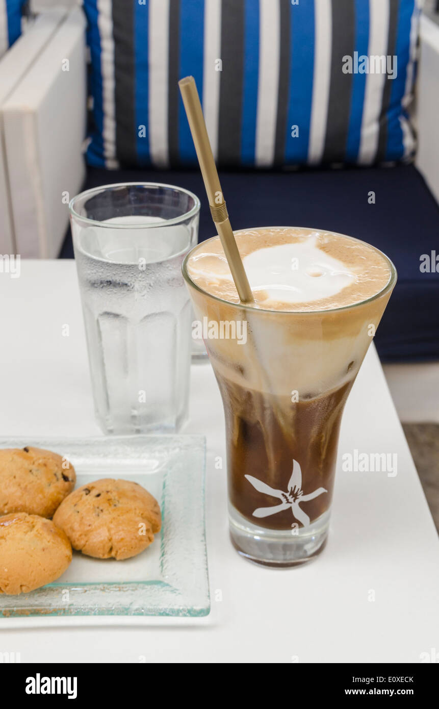 Eiskaffee, ein Glas Wasser mit einigen Keksen auf einem Tisch in Griechenland Stockfoto