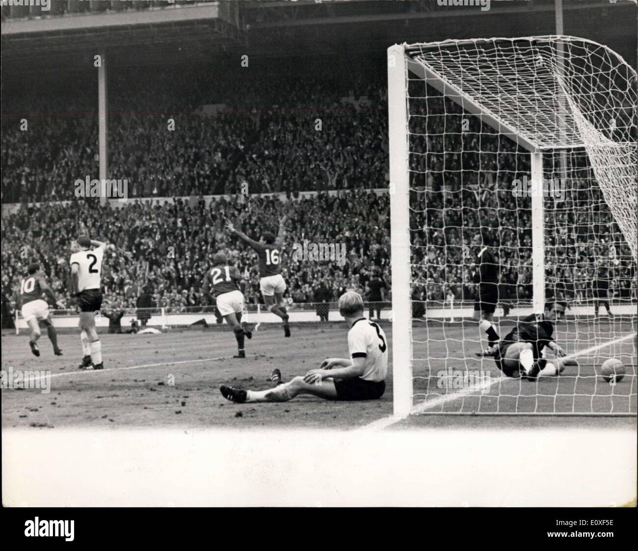 30. Juli 1966 - Fußball-WM. England im Vergleich zu Westdeutschland Weltcup-Finale im Wembley-Stadion. Foto zeigt: England? s Martin Peters (Nr. 16) wirft seine Arme und springt in die Luft, als er England punktet? s zweite Tor während Jagd (Nr. 21) von England überfährt, um ihm zu gratulieren. Durch die Torpfosten ein wenig niedergeschlagen sitzt Schnellinger, der deutschen Außenverteidiger während der deutsche Torwart Hans Tilkowski für den Ball im Netz erreicht. Stockfoto