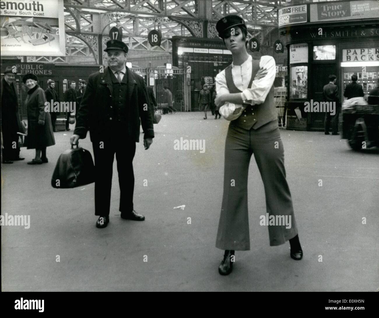 12. Dezember 1966 - das Modell mit dem Aussehen eines Trägers, die Waterloo Station aufgehellt; Das Mädchen gegenüber Plattform 17 wird nicht Ihre Tasche Luft tragen. Sie dachte, sie British Railways neue Idee eines Trägers und eine gute Idee damals war. So die Passagiere auf der Londoner Waterloo Station als ein Modell erschien tragen was soviel wie ein Portier Uniform sah. Aber das Outfit, das Modell trug, war die aktuelle Modeerscheinung - eine kleine alte Hosenanzug mit Weste für Mädchen, auf Partys zu tragen Stockfoto