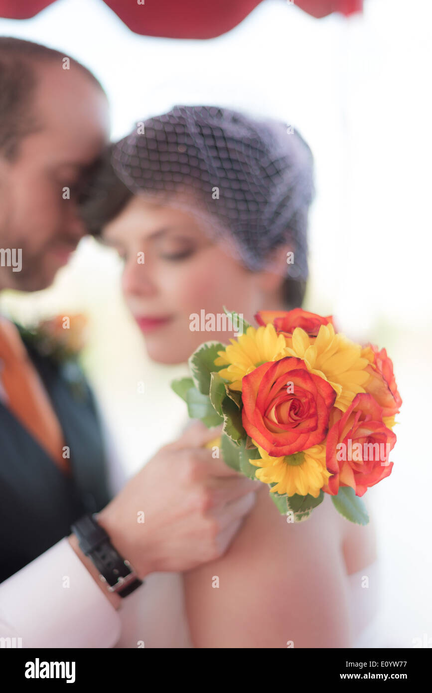 Braut und Bräutigam im Hintergrund mit Blumenstrauß auf dem display Stockfoto