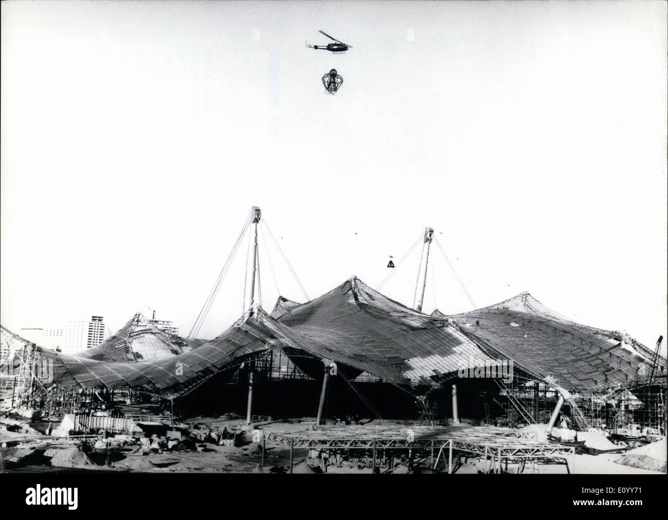 11. November 1971 - Topping-Up Zeremonie auf die Olympischen Gebäude Sitw in München: 10 Monate vor der geplanten Eröffnung der Olympischen Spiele 1972, die Arbeiter auf der Baustelle heute feierte die Fertigstellung der gigantischen Dach des Stadions. Ein Hubschrauber hebt die speziell angefertigte '' Krone '' aus Stahl und Girlanden auf das Dach. Danach wurden die internationale Arbeitskräfte von 5000 Männern Freibier und Erfrischungen behandelt. Stockfoto