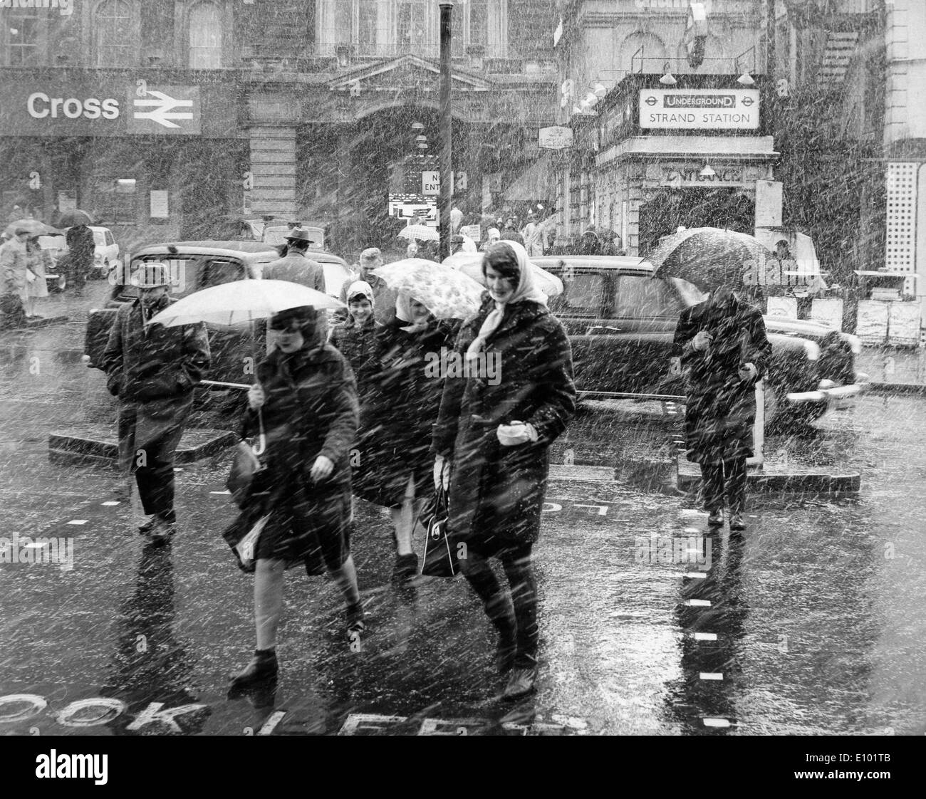 Schlechtwetter - eilen Stadtbewohner in England auf einem windigen Regen fegte Straße mit Sonnenschirmen. Stockfoto
