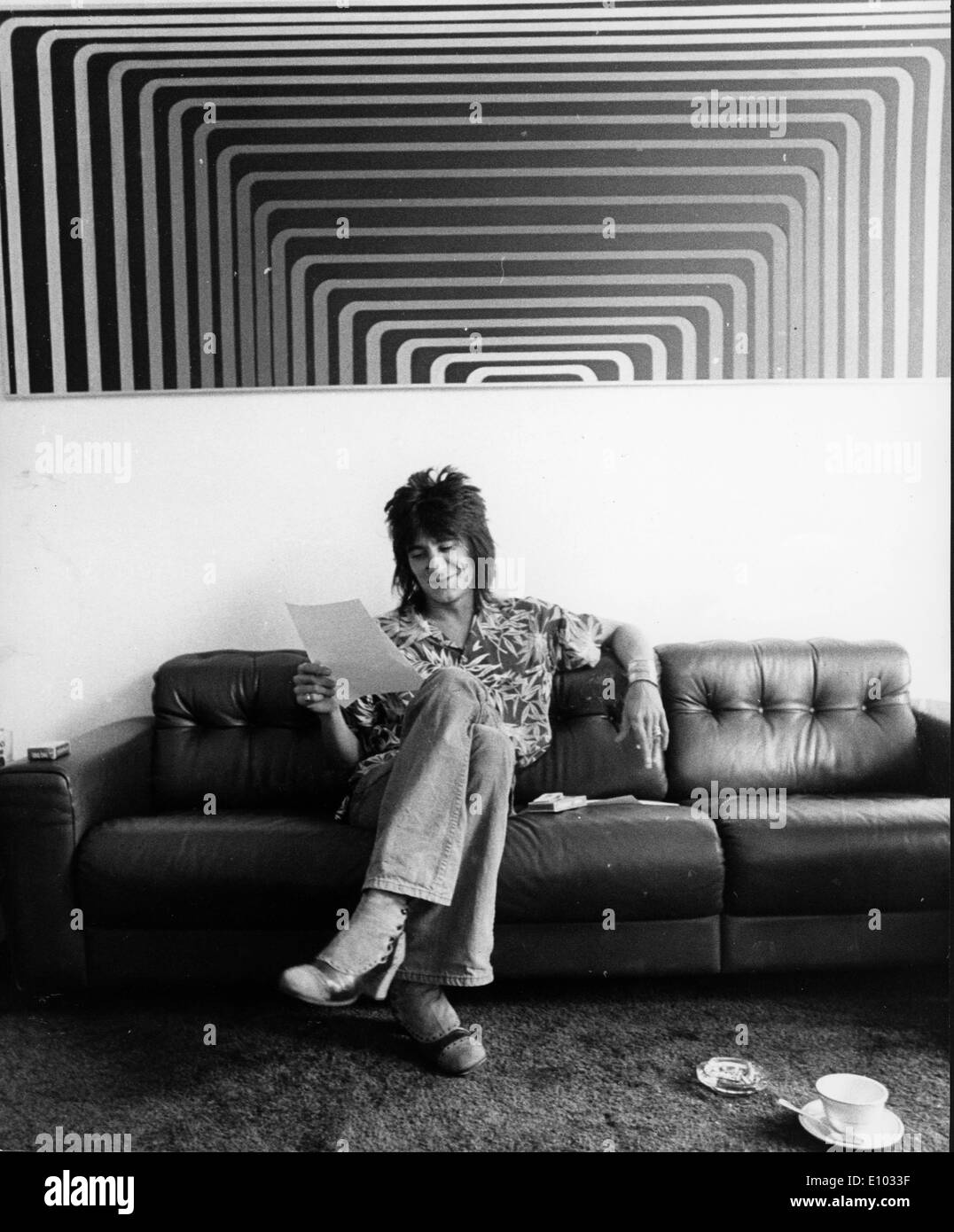 Gitarrist Ronnie Wood liest auf seiner couch Stockfoto