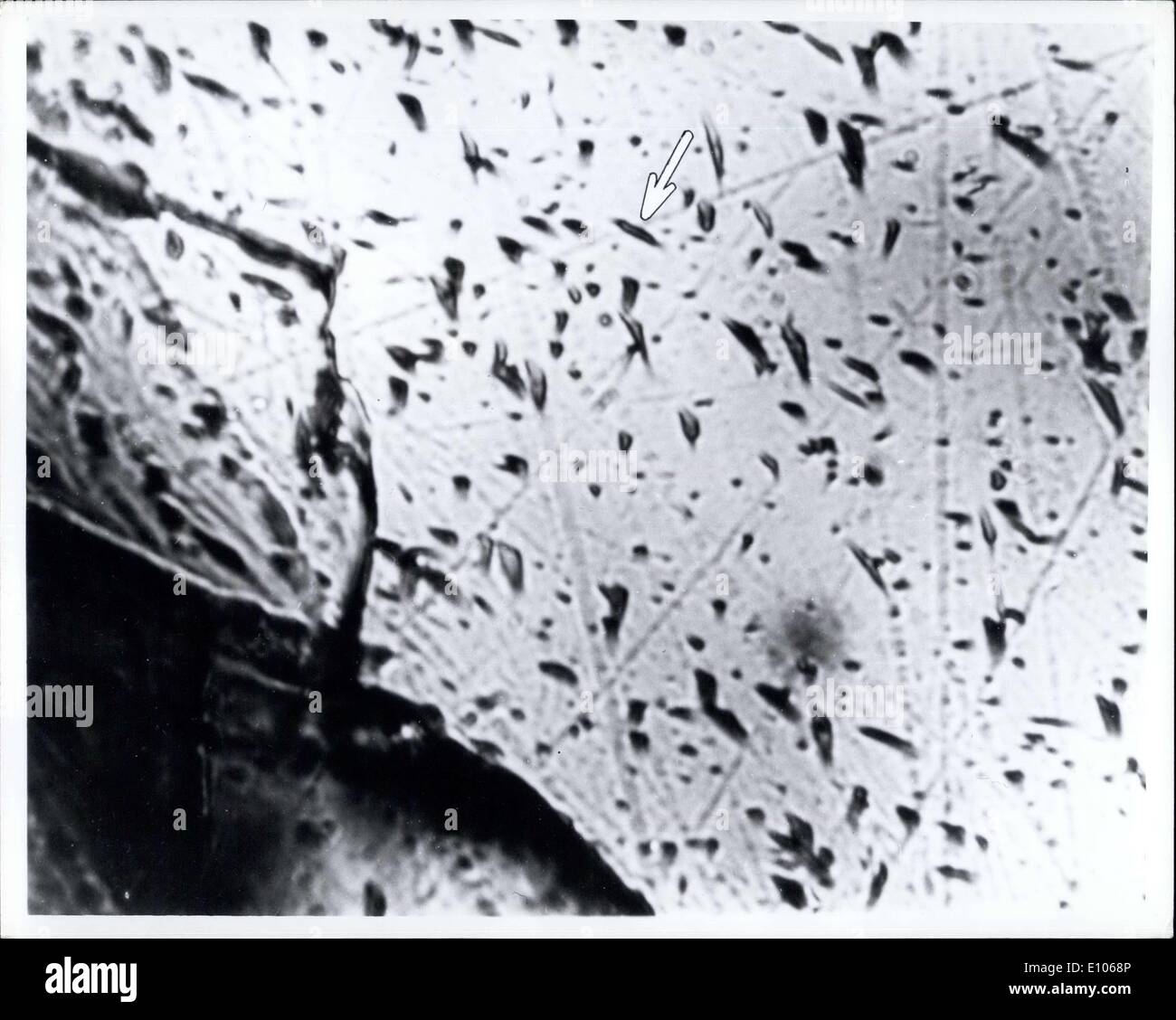 5. Januar 1970 - durch Ätzung Fragmente von lunar Material gesammelt durch die Apollo 11 Astronauten, Wissenschaftler bei der General Electric Research und Development Center haben festgestellt, dass die Felsen gespickt sind, mit Spuren, die durch kosmische Strahlung, geladene Teilchen, die die Erde und der Mond unablässig aus allen Richtungen in den Weltraum zu bombardieren. Studie der Tracks kann Hinweise auf den Ursprung der kosmischen Strahlung, jetzt ein ungelöstes Rätsel geben. Der Pfeil zeigt auf eine typische kosmischer Strahl zu verfolgen. Stockfoto