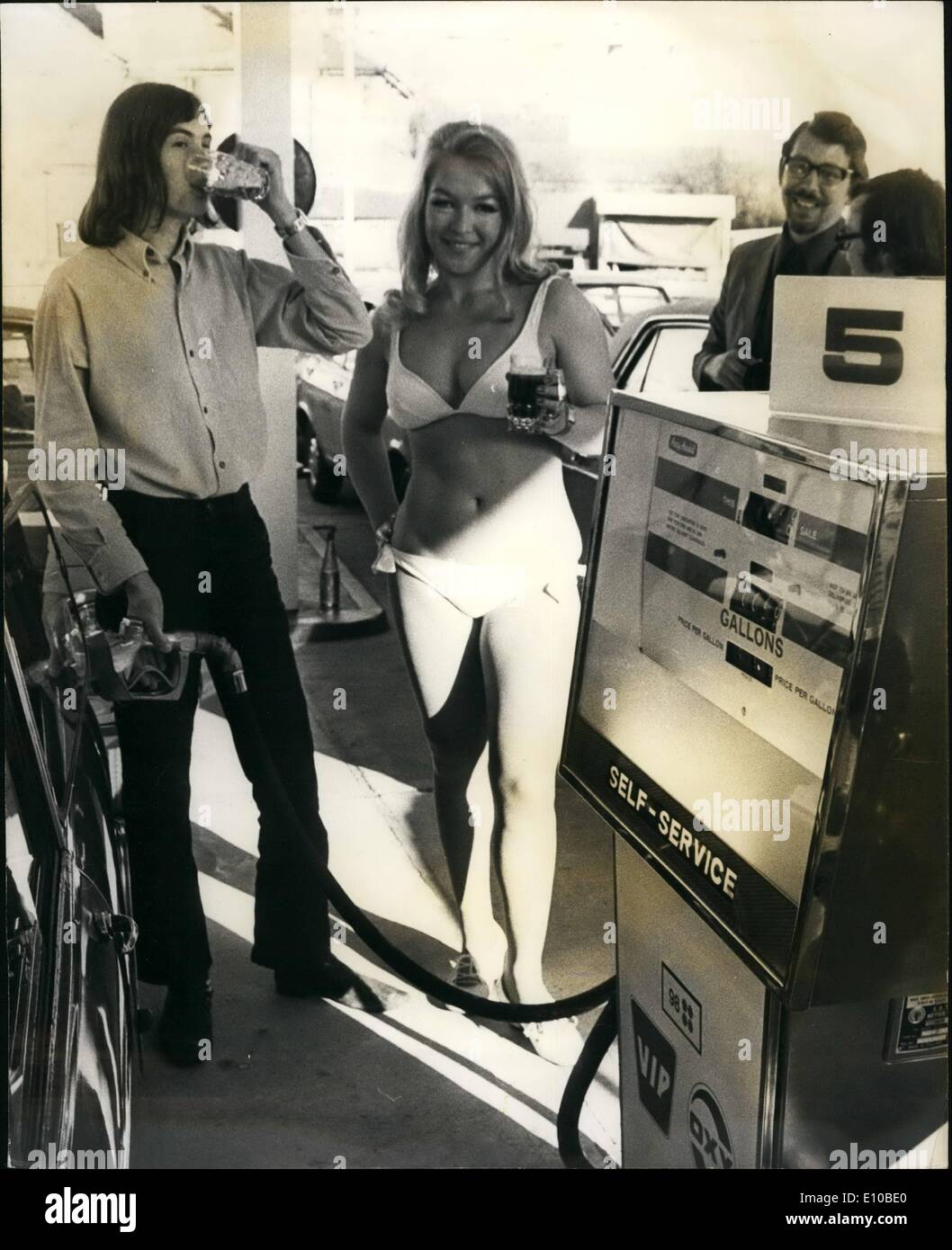 3. März 1972 - ein Kuss oder Bier für Autofahrer Benzin an neue Garage in St. Albans kaufen: bei der Eröffnung der neuen Selwood Garage Hatfield Road, St Albans, gestern, Bikini-Girls gab Freibier eines Kusses für Autofahrer Benzin, Öl, Zigaretten und andere Accessoires zu kaufen. Foto zeigt, wie ein Kunde Put Benzin ist in seinem Auto er trinkt sein Bier, mit einem Bikini-Mädchen hält ein Bier für den nächsten Kunden. Stockfoto