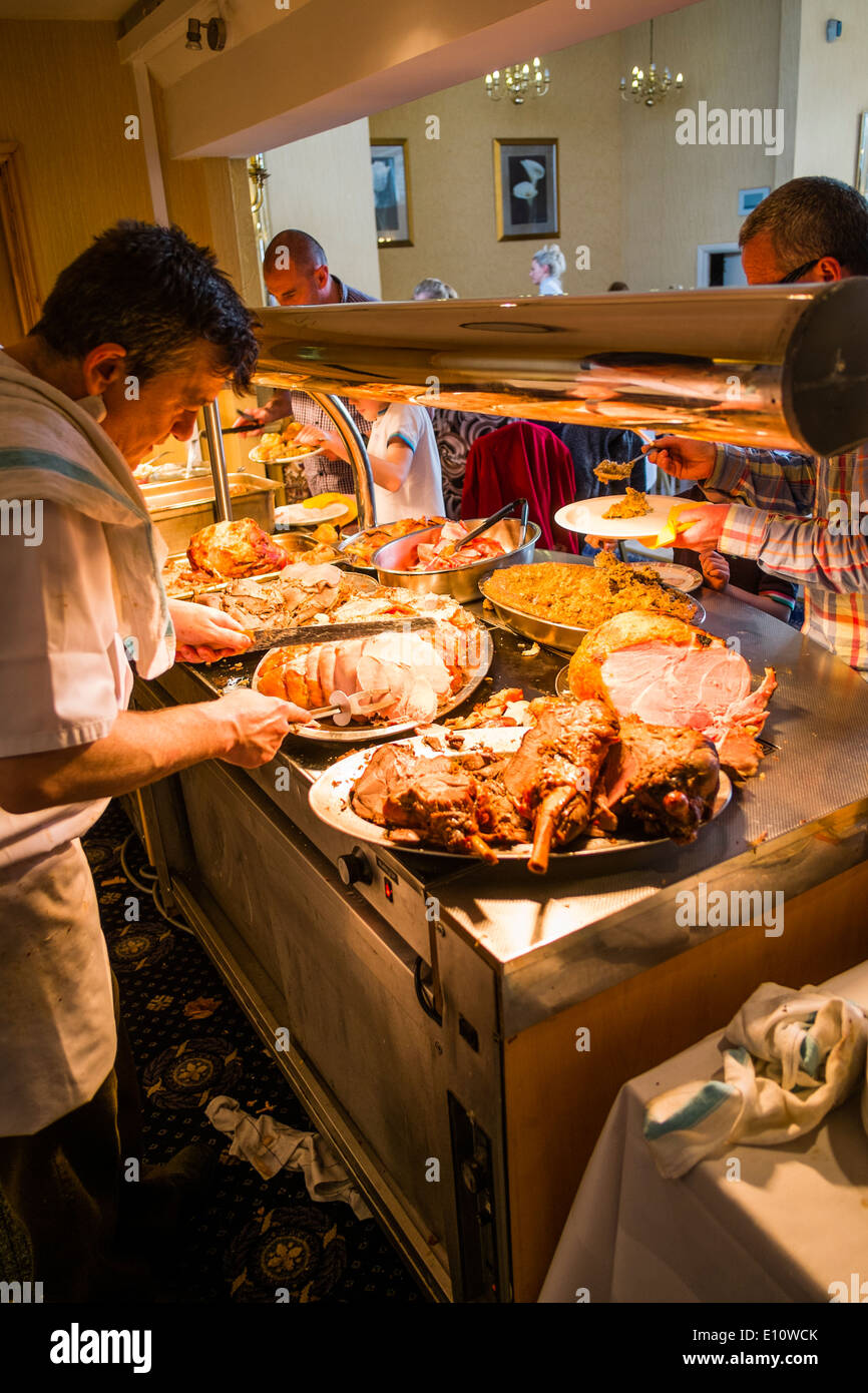 Ein Chefkoch am Arbeitsplatz schnitzen Gelenke von Fleisch auf einen Sonntag Mittagessen Abendessen Buffet in einem UK-Hotel-restaurant Stockfoto