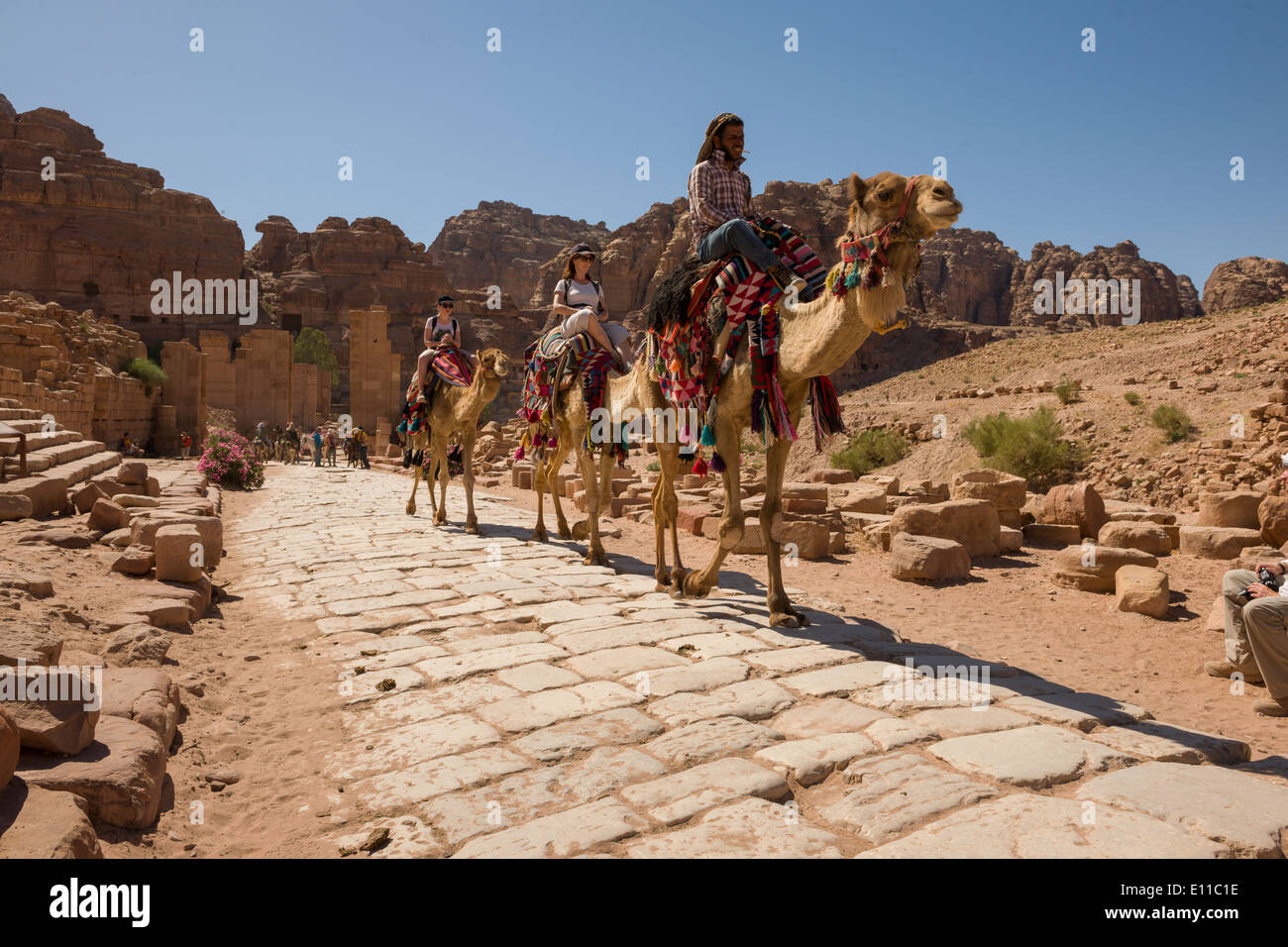 Touristen und Beduinen auf Kamelen auf die Colonnaded Straße, Petra, Jordanien Stockfoto