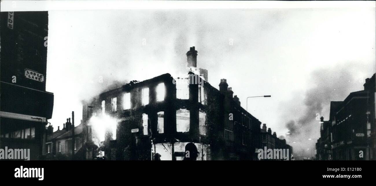 7. Juli 1981 - Unruhen In Toxteth: Flammen von einem ausgeschlachteten Gebäude in Toxteth, in der Nähe von Liverpool, mit einsamen Polizisten Wache nach einer langen Nacht Unruhen durch Hunderte von schwarzen und weißen Jugendlichen noch springen. Stockfoto