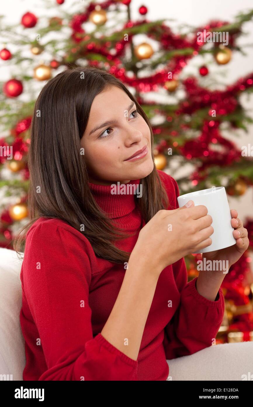 3. Oktober 2009 - 3. Oktober 2009 - attraktive Brünette vor Weihnachten Baum halten Tasse Kaffee Stockfoto
