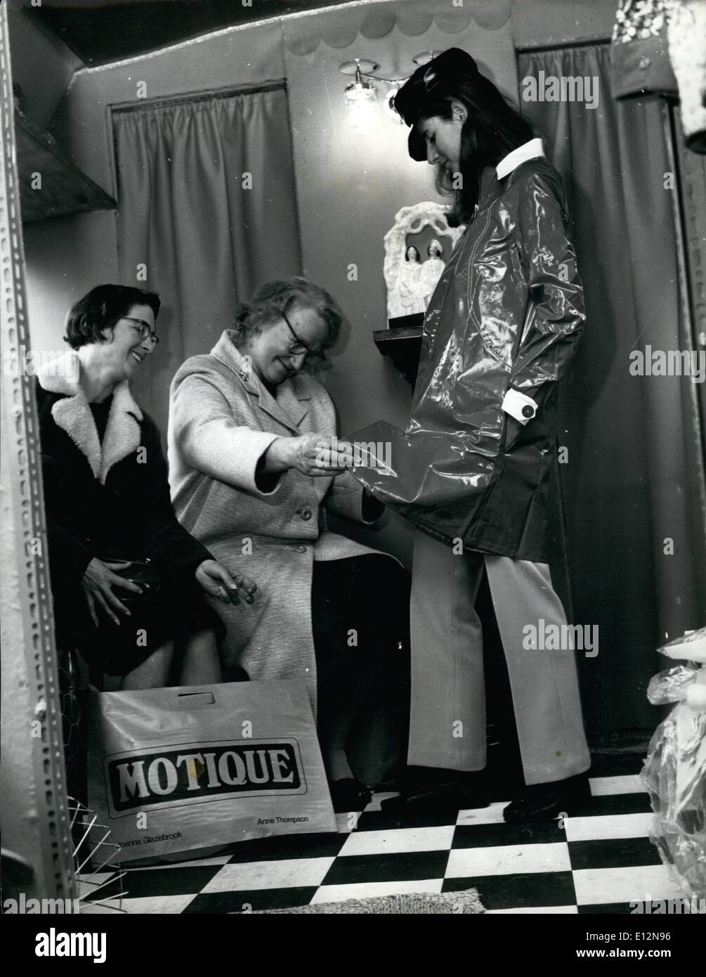 24. Februar 2012 - sind zwei Kunden in der Motique einen näheren Blick auf die glänzenden Regen-Kosten von Modell Frances Gesang getragen. Stockfoto