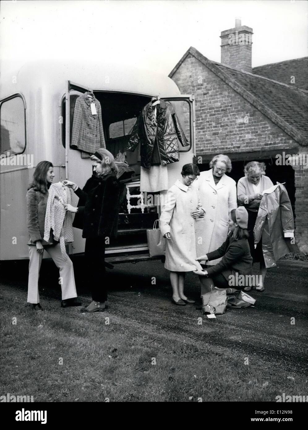 24. Februar 2012 - beschreibt Vertrieb Dame Veronica Markes (schwarze Hose) eine Kleidungsstück mit einem Kunden. Anzüge und Kunststoff Mac werden an den Türen angezeigt. Joanna Glazebrook berät bei Hemlengths (rechts, tragen Hose-Anzug und Mütze) Stockfoto