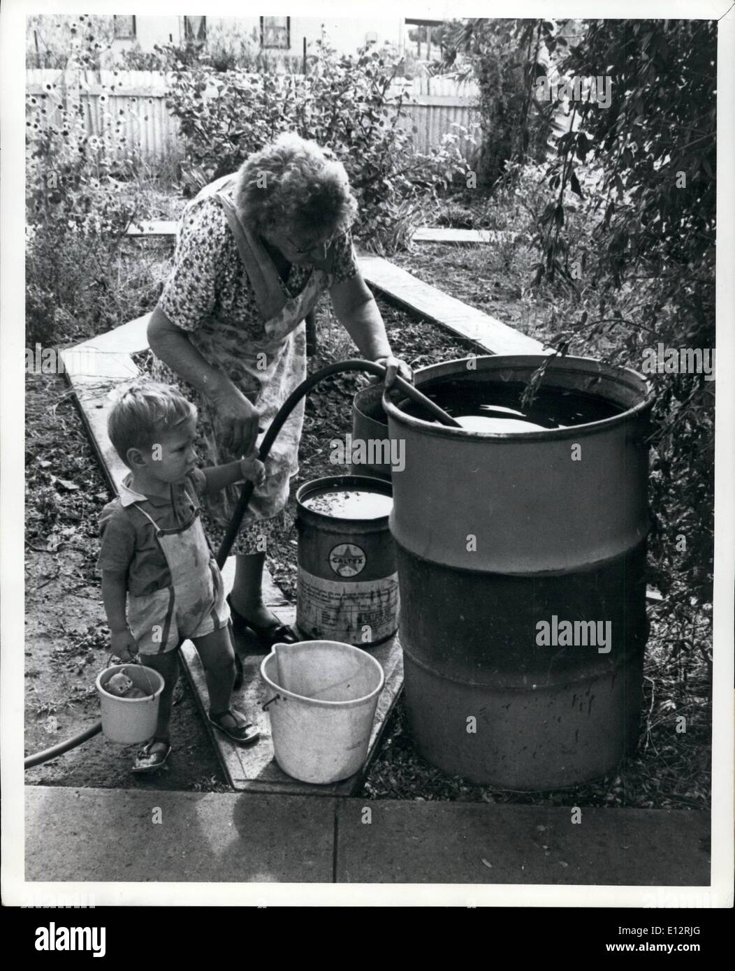 25. Februar 2012 - füllt Frau E.J.Dwyer, beobachtet von Enkel Raymond Colvin, ihr 44-Galon Trommel nach der Ankunft des Zuges Tullibigeal Wasser. Stockfoto