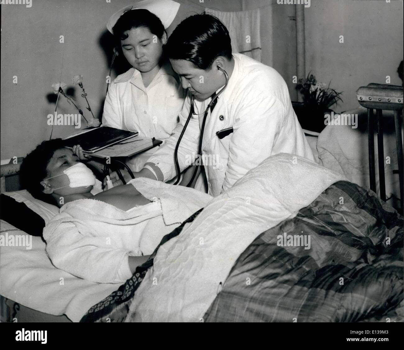 29. Februar 2012 - '' mutigen Arzt '' auf seiner Visite: mit seinen Krücken gelehnt die Gemeinde Mauer und seine Krankenschwester Assistentin steht mit seinen Notizen, Dr. Watanabe untersucht, einer seiner Patienten. Stockfoto