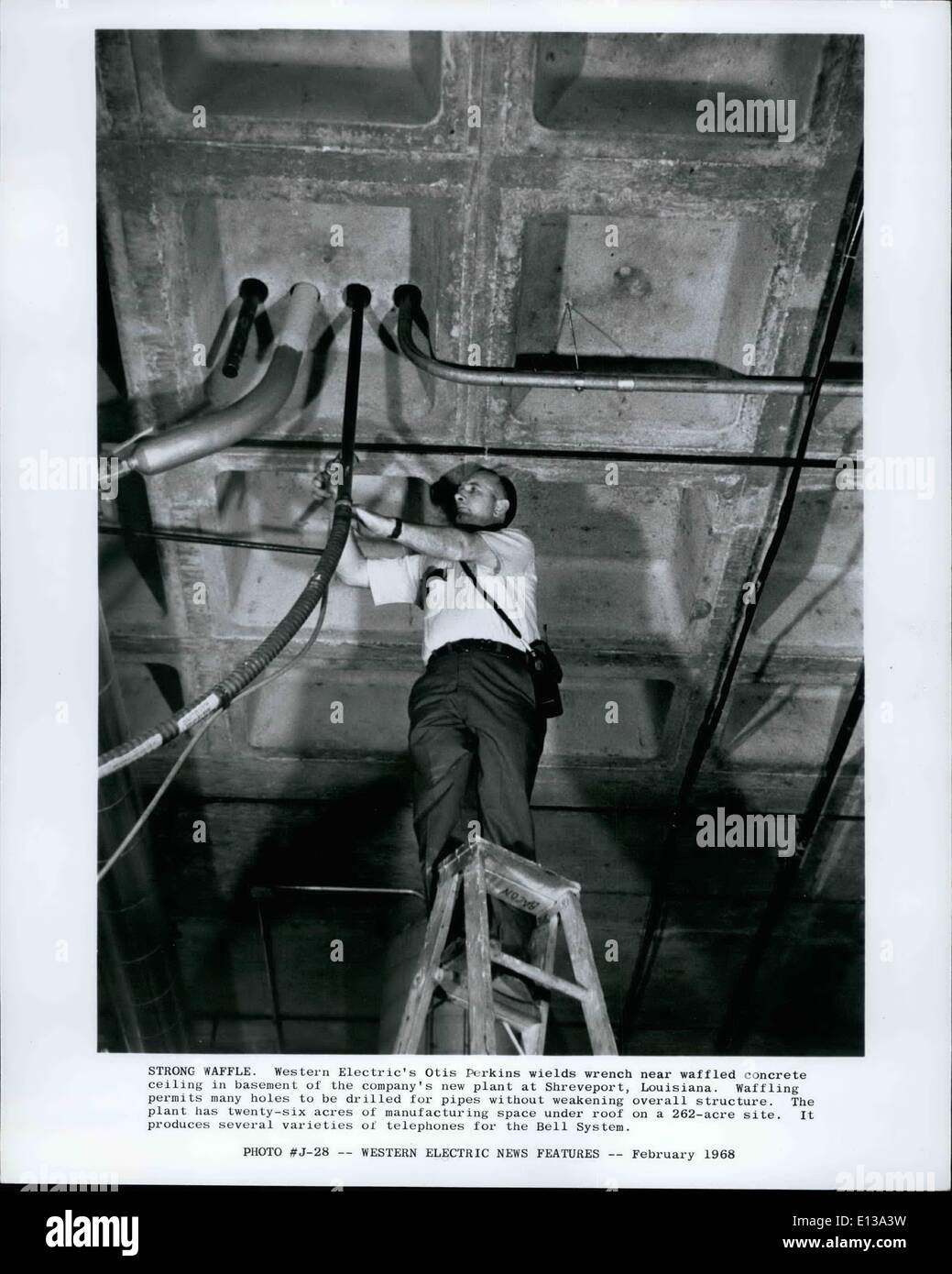 29. Februar 2012 - starke WAPPLE: Western Electric Otis Perkins übt Schraubenschlüssel in der Nähe von Waffelmuster Betondecke im Untergeschoss des neuen Werk des Unternehmens in Shreveport, Louisiana, Waffling erlaubt viele Löcher für Rohre ohne Schwächung Gesamtstruktur gebohrt werden. Die Pflanze hat 26 Hektar Produktionsfläche unter Dach auf einem 262-Hektar großen Gelände. Es produziert verschiedene Sorten des Telefons für Bell Sysyem. Stockfoto