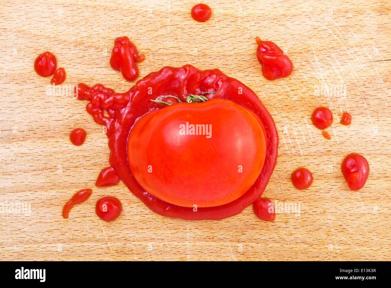 Tomaten-Ketchup auf Holzbrett. Bespritzt Tomate mit Ketchup auf Schneidebrett Küche. Stockfoto