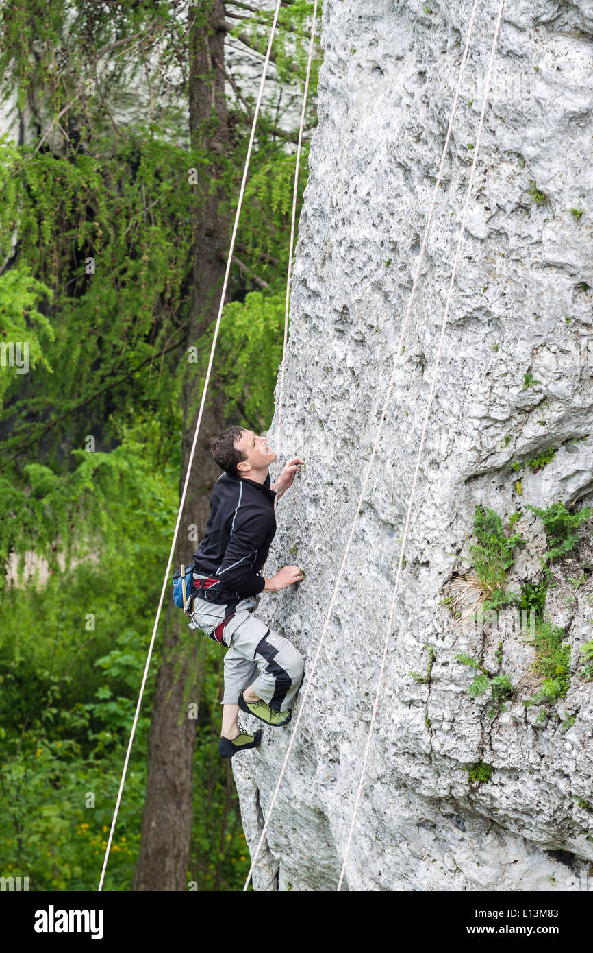 Mann, die steilen und hohen Felswand klettern. Stockfoto